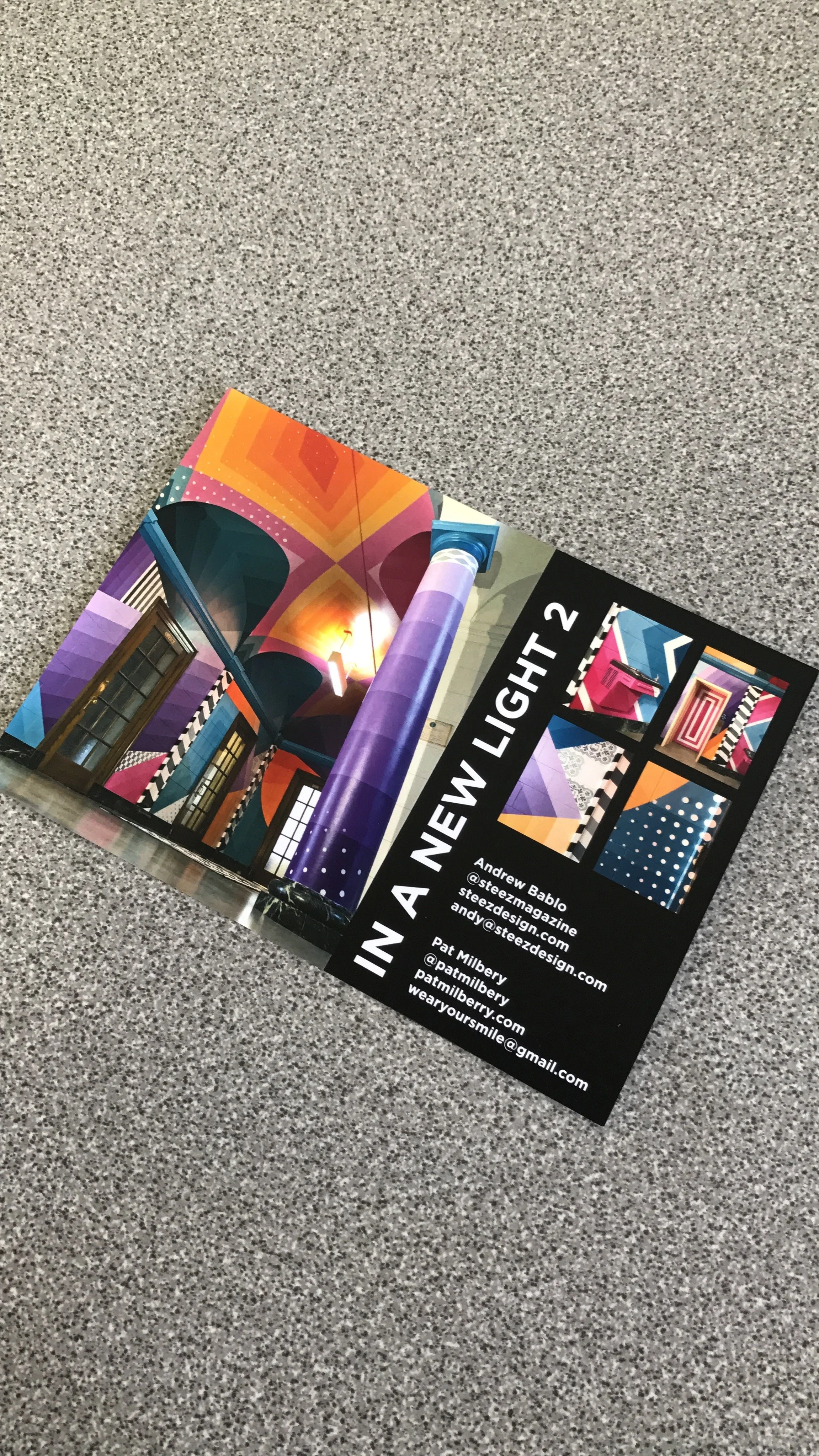 Colorful geometric art magazine or brochure on a gray speckled floor