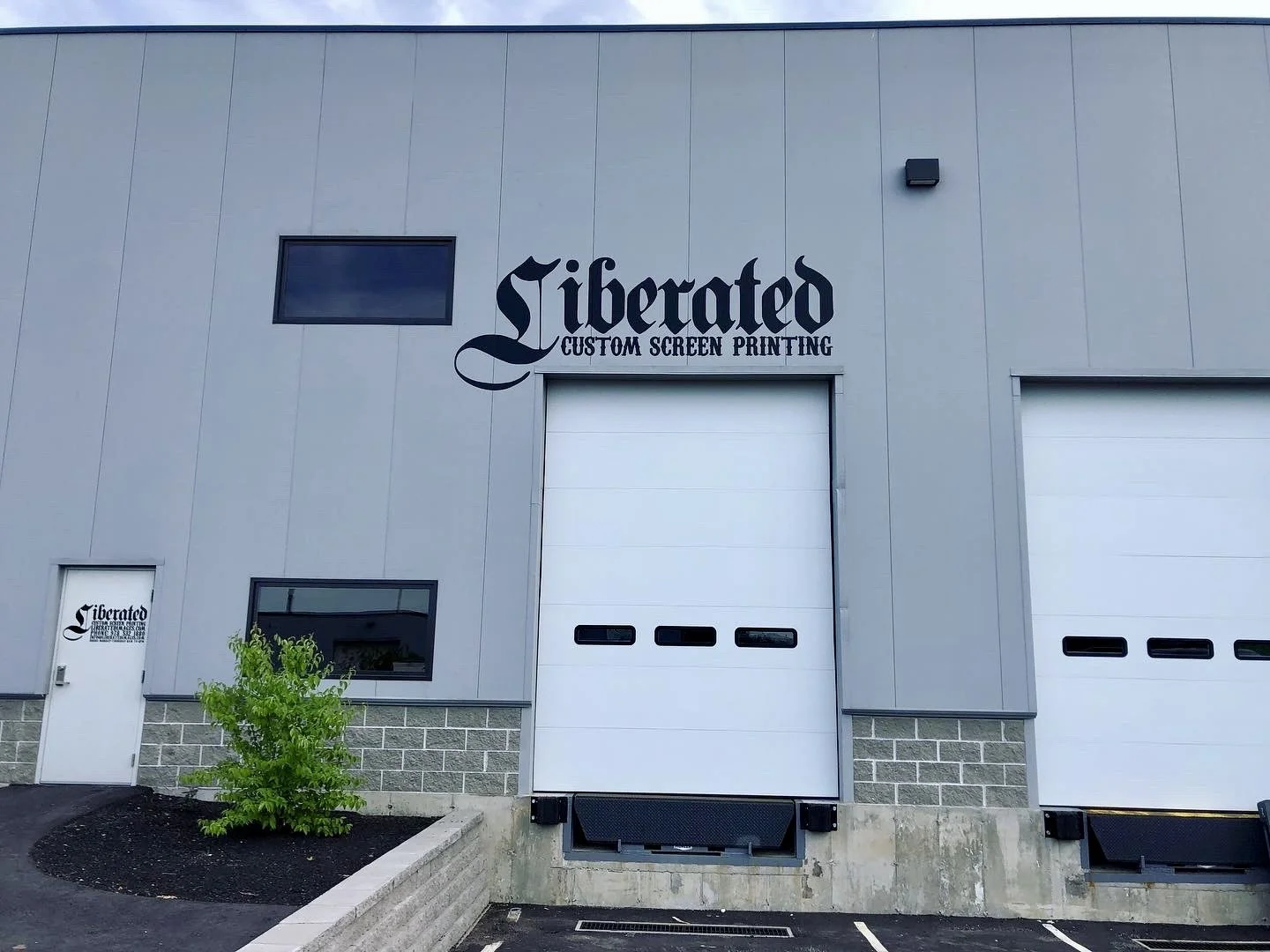 Exterior of Liberated Custom Screen Printing shop with loading bay doors