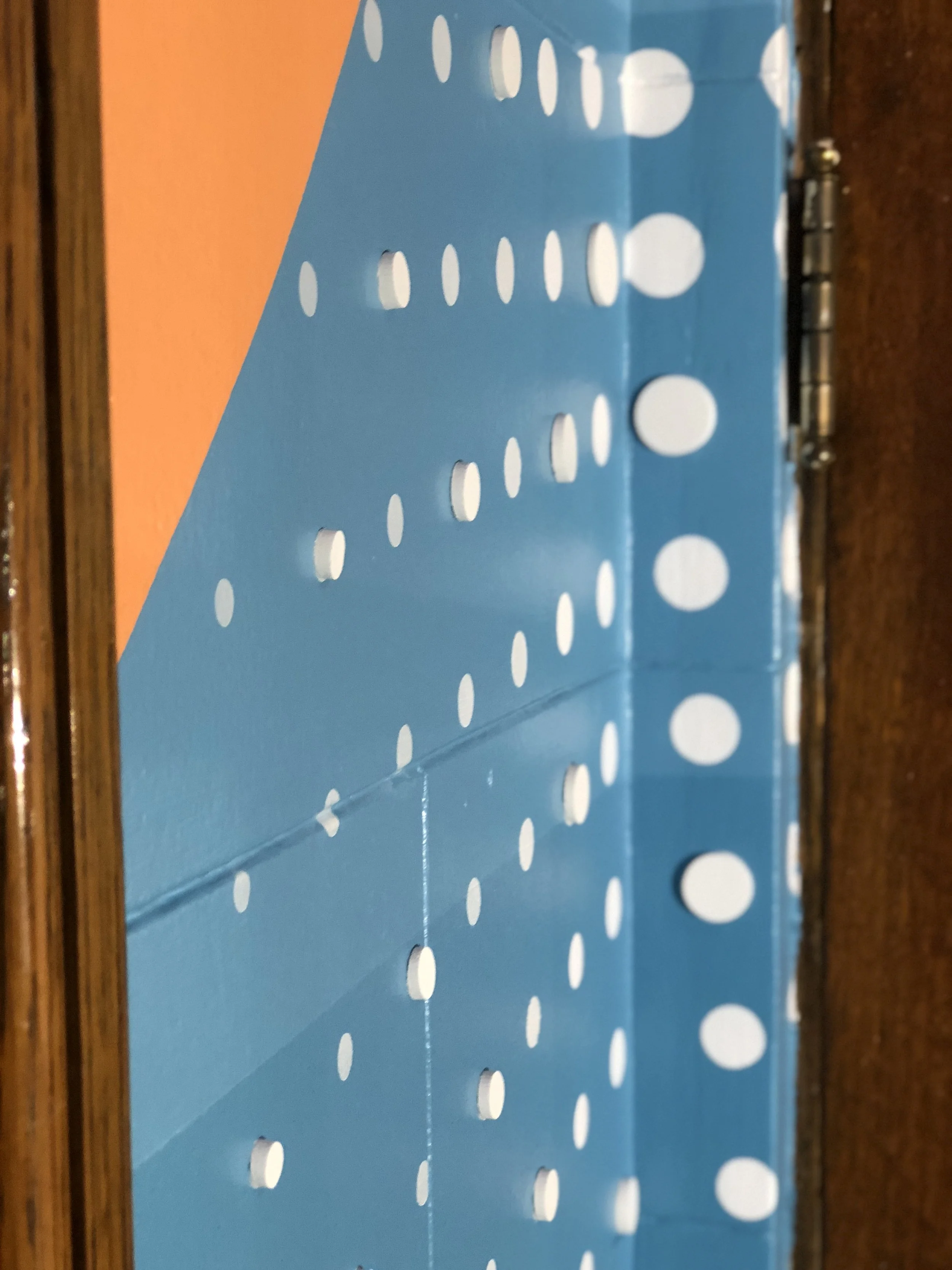 Close-up of a blue patterned curtain with white dots beside a wooden doorframe