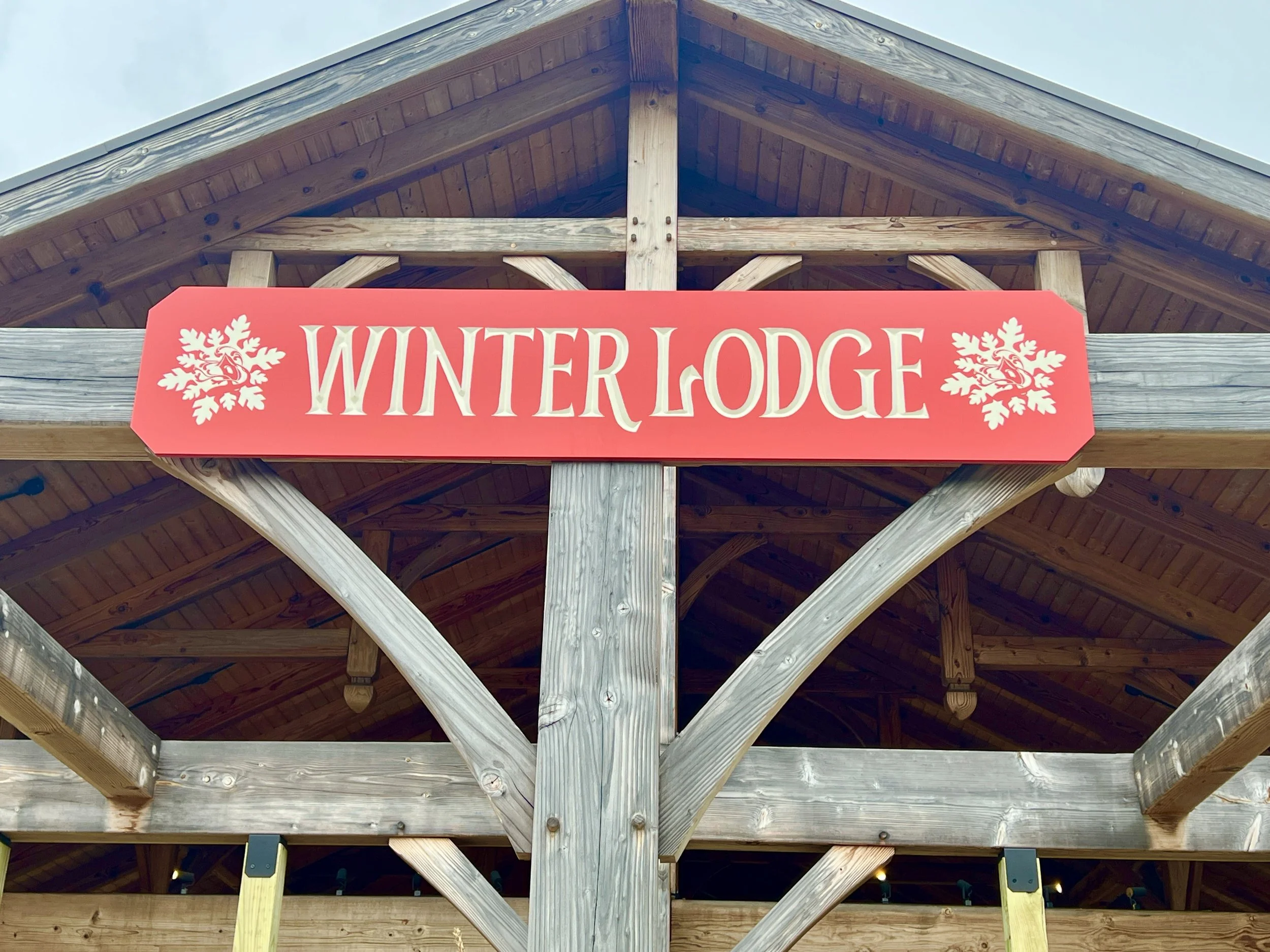 Red Winter Lodge sign mounted on the timber frame of a rustic wooden pavilion