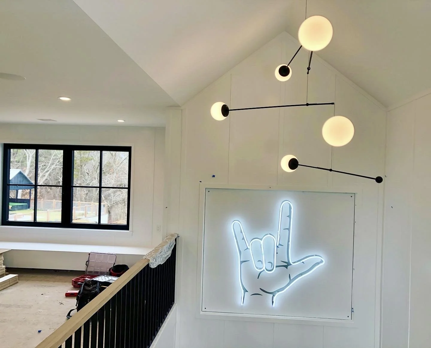 Modern white interior with spherical pendant lights and a glowing neon rock-and-roll hand sign