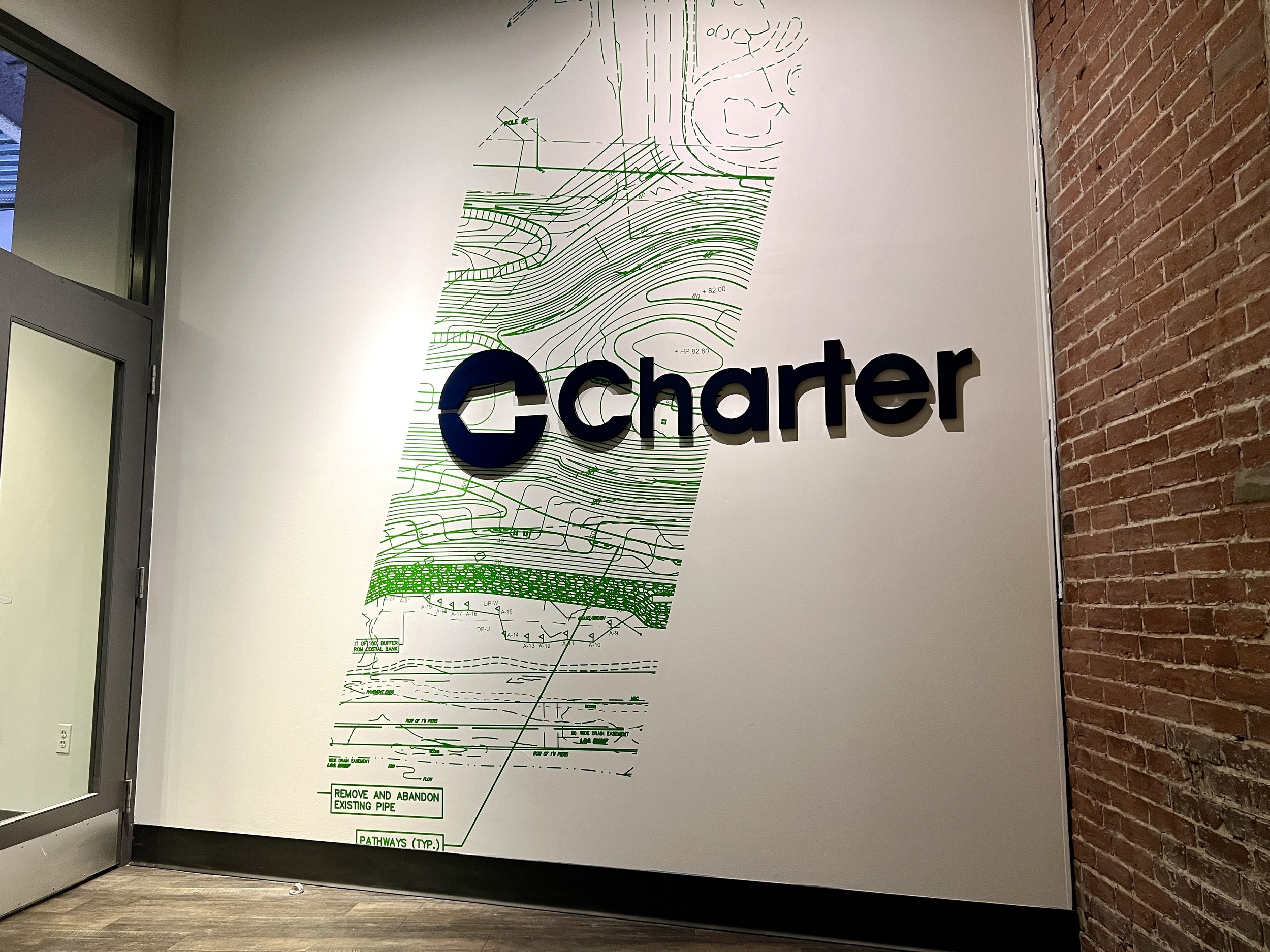 Charger logo mounted over a green engineering site plan on an office wall