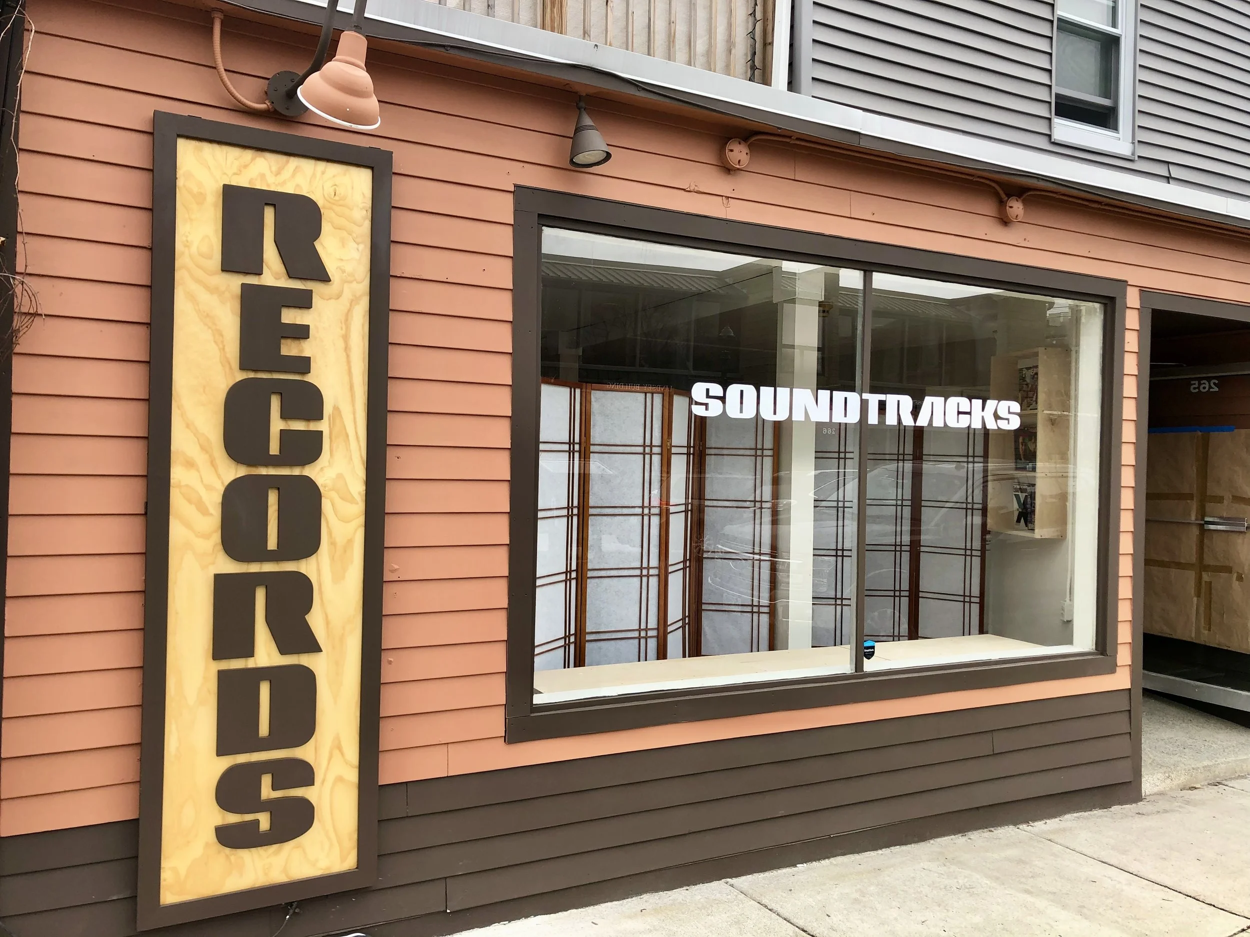 Exterior storefront with a vertical repair sign, large window, and white “SOUNDTRUCKS” lettering.