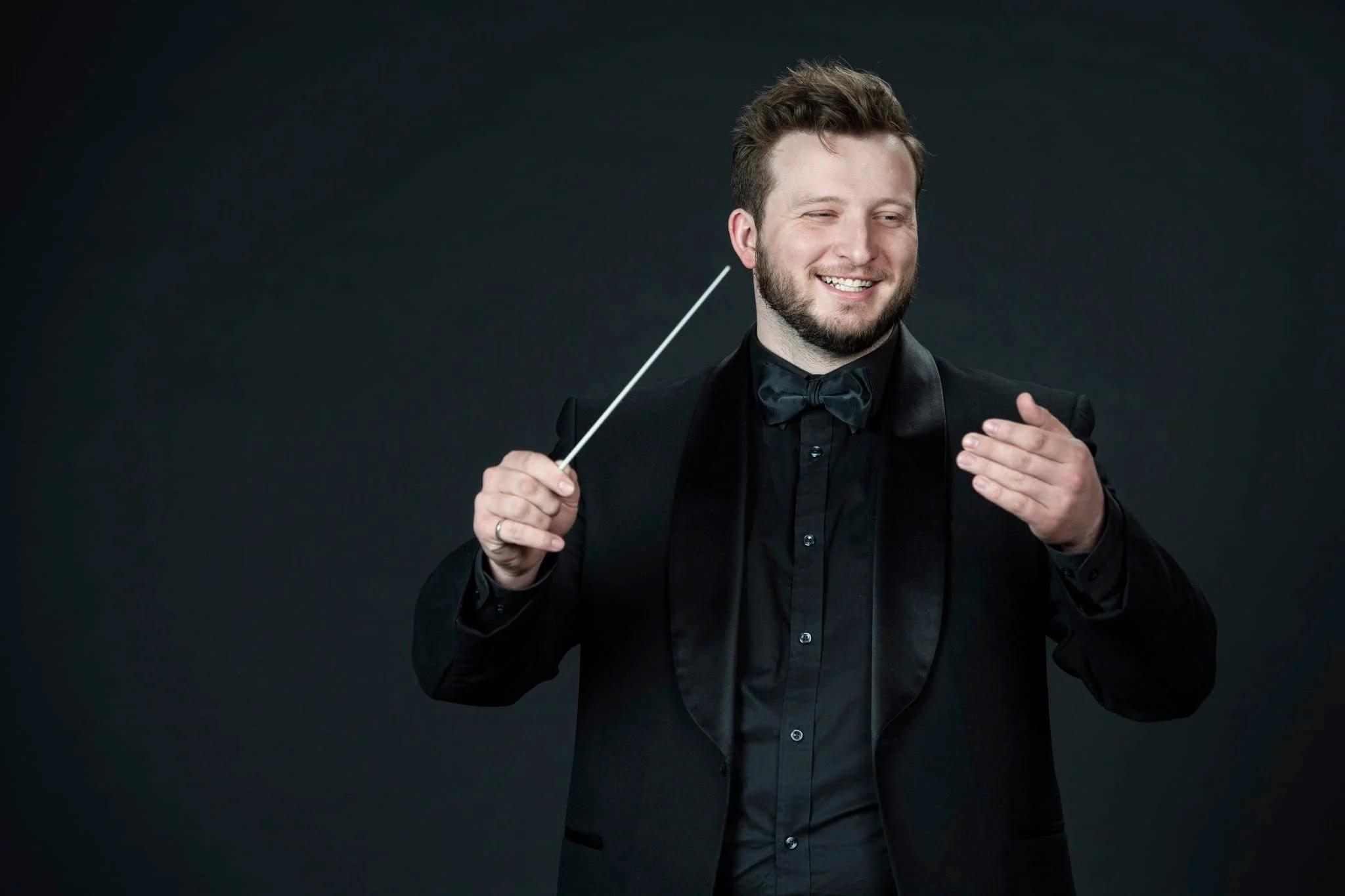 Jake South smiling and holding a conducting baton