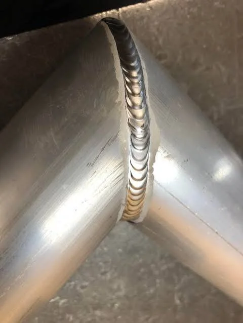 Close-up of a welded metal joint connecting two metal pipes.