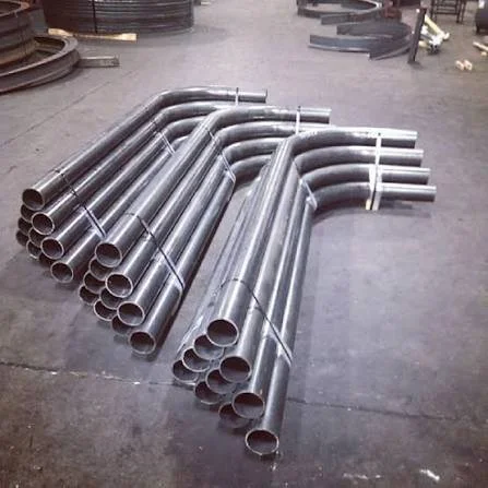 A collection of metal pipes arranged on the floor in a workshop or manufacturing setting.