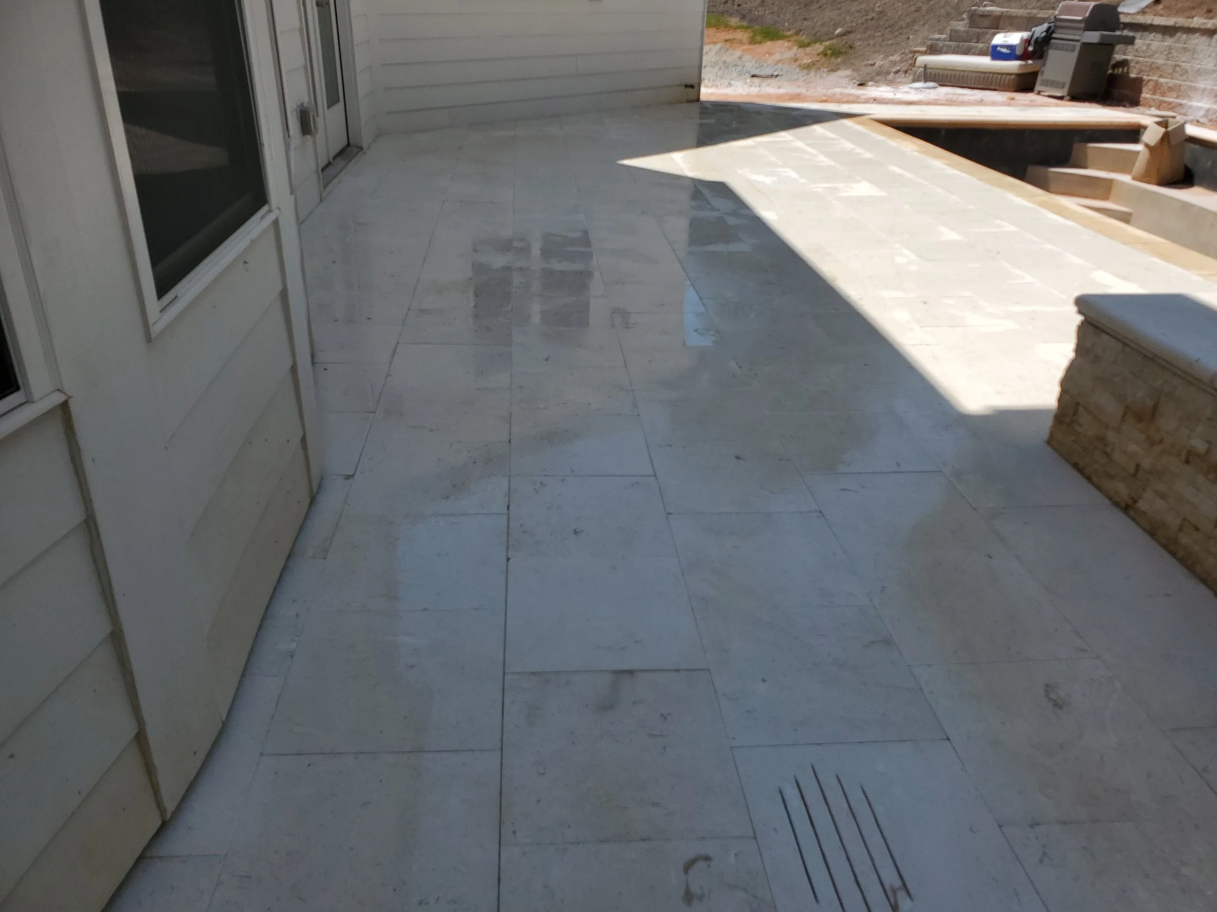 Back patio with tiled floor, a sliding glass door, and an outdoor area under construction with tools and materials visible.