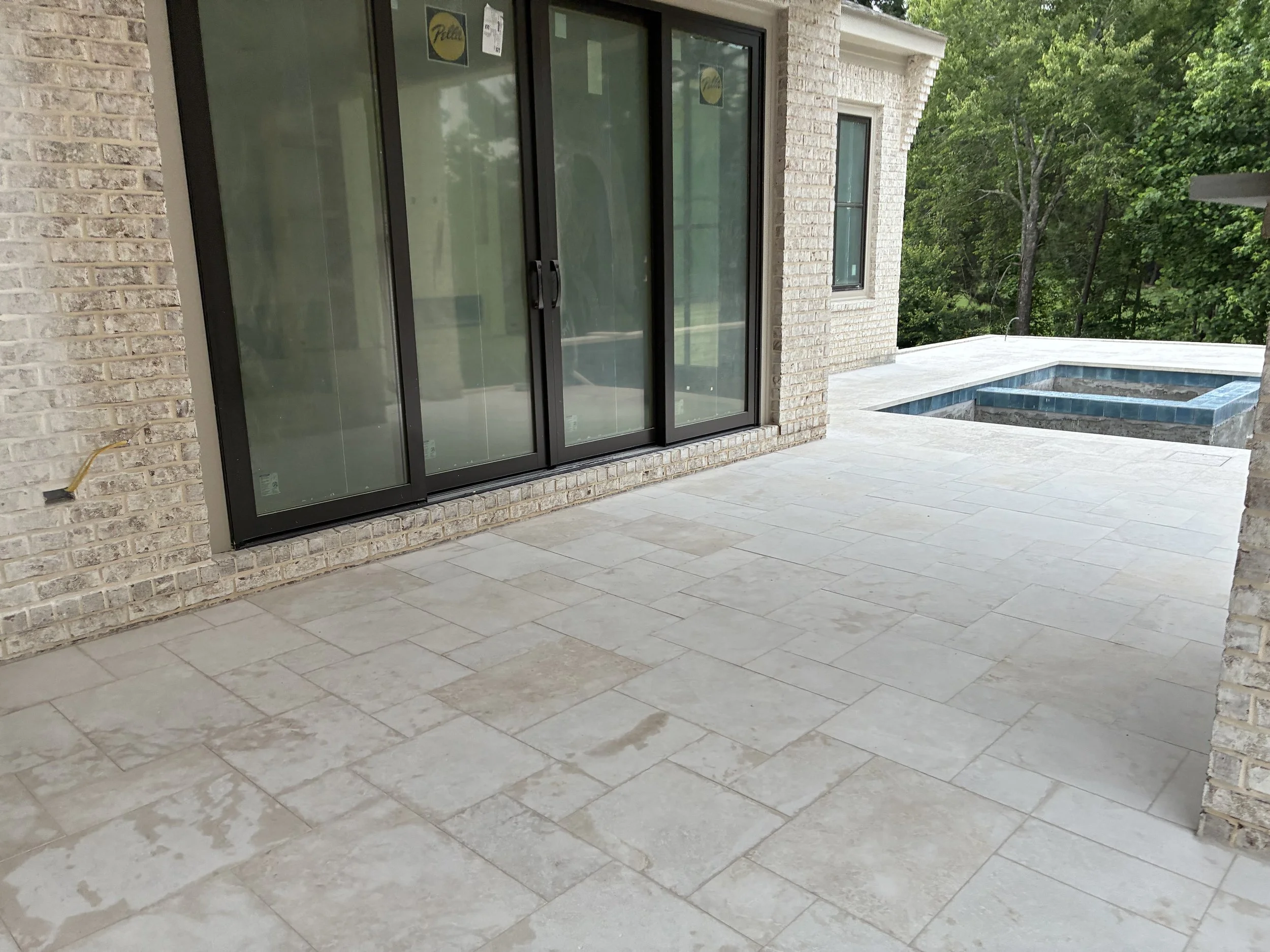 Porch area with sliding glass door and a small in-ground pool, surrounded by trees and greenery.