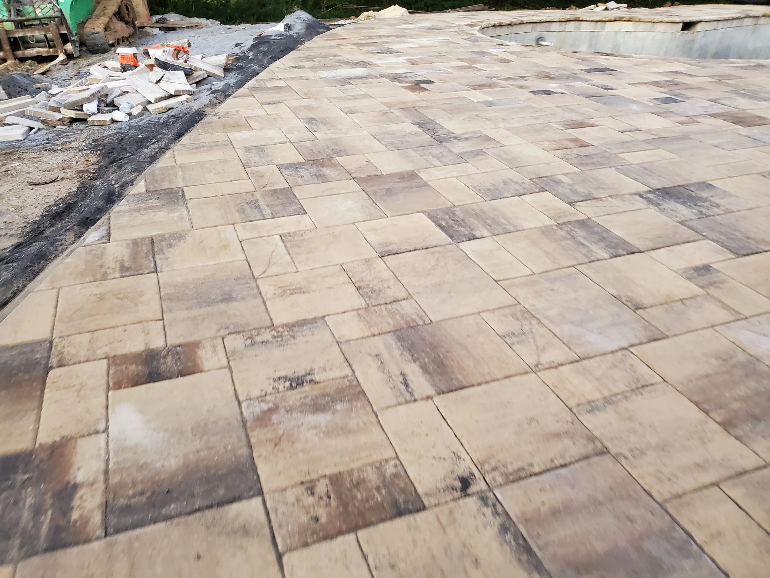 Newly paved stone patio in progress with some construction materials and gravel on the side.