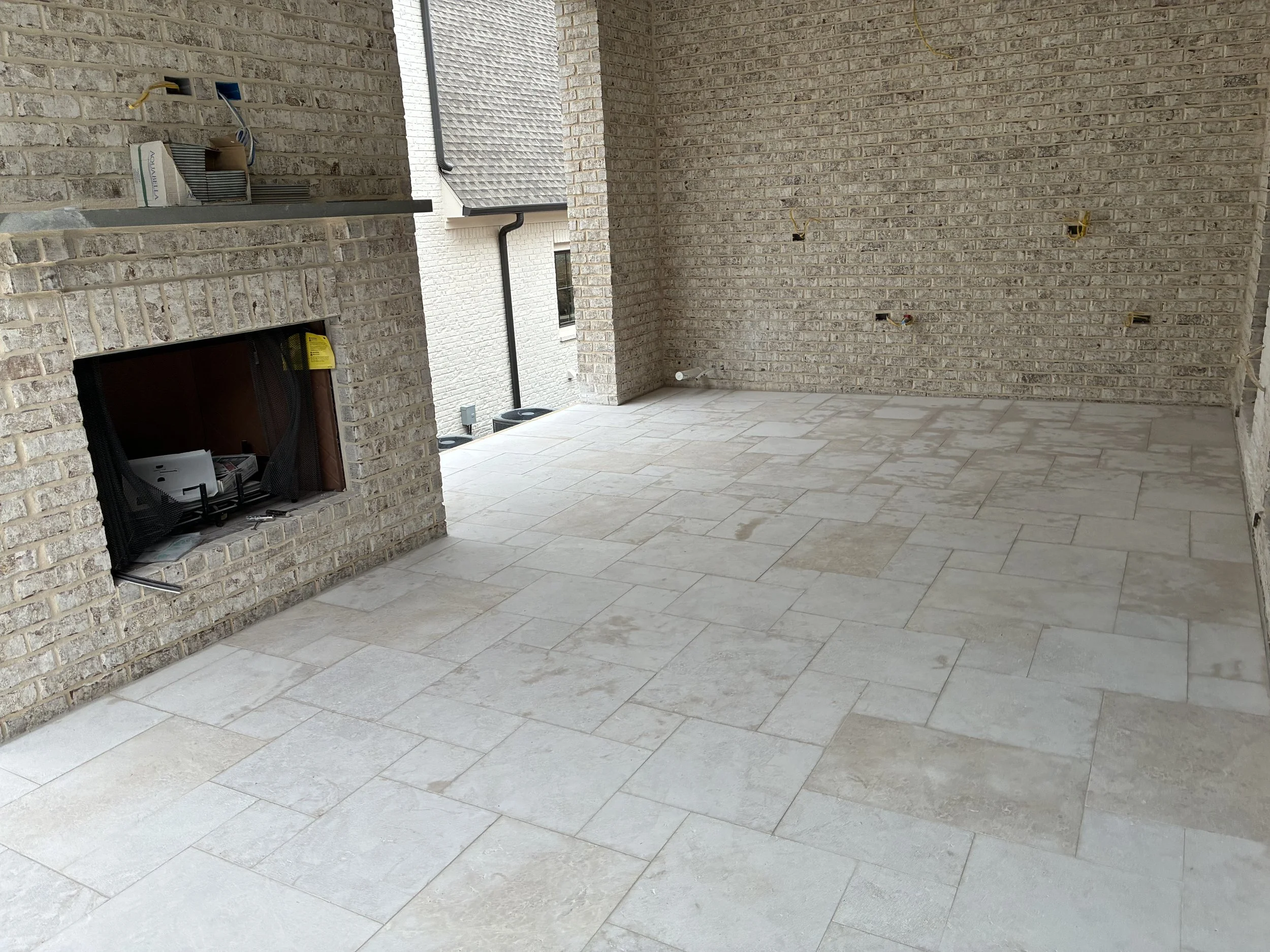 Interior of a house under construction with exposed brick walls, electrical wiring, and a tiled floor.