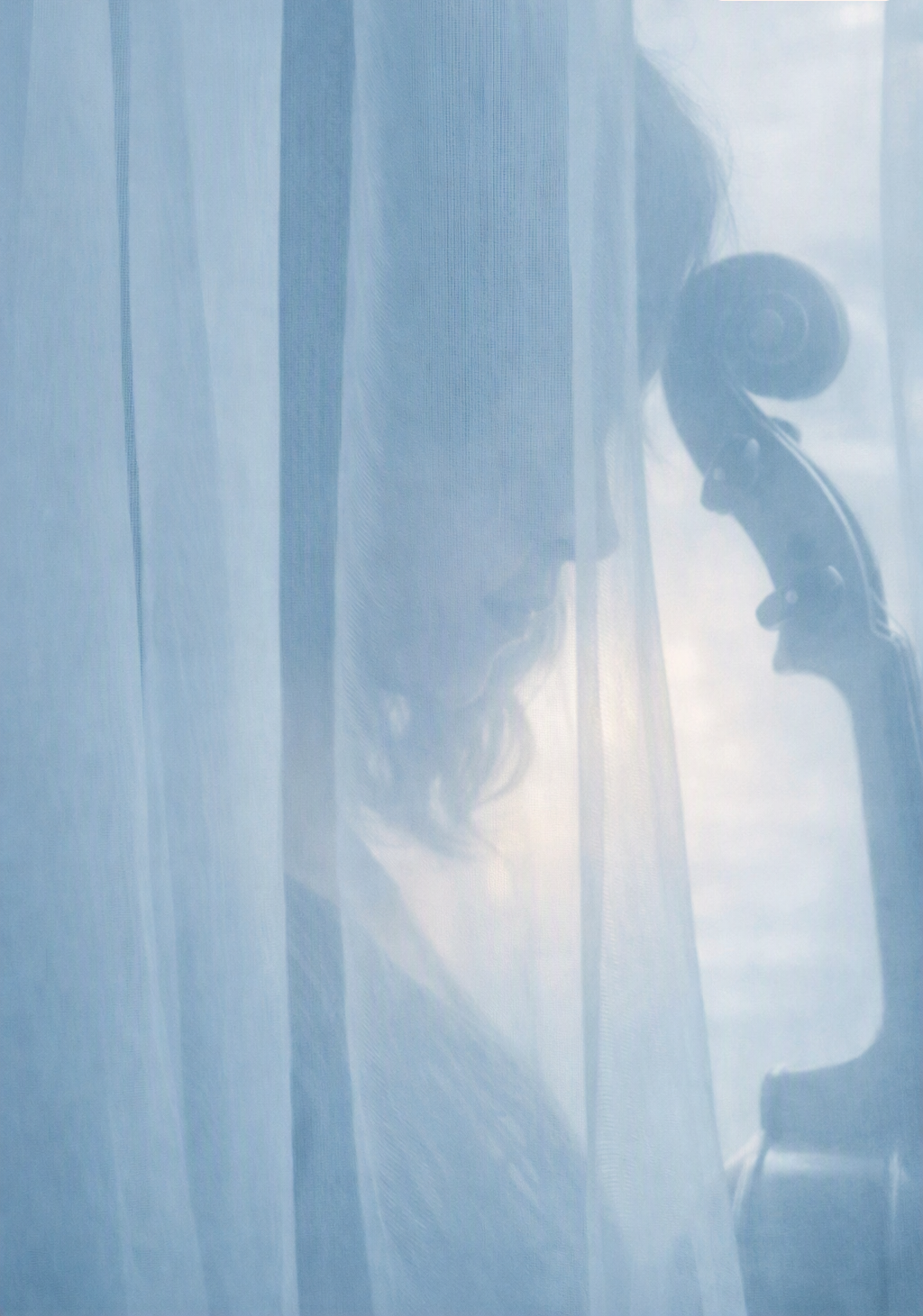 Person wearing a face mask and headphones, looking at a vintage telephone through a semi-transparent curtain or fabric.