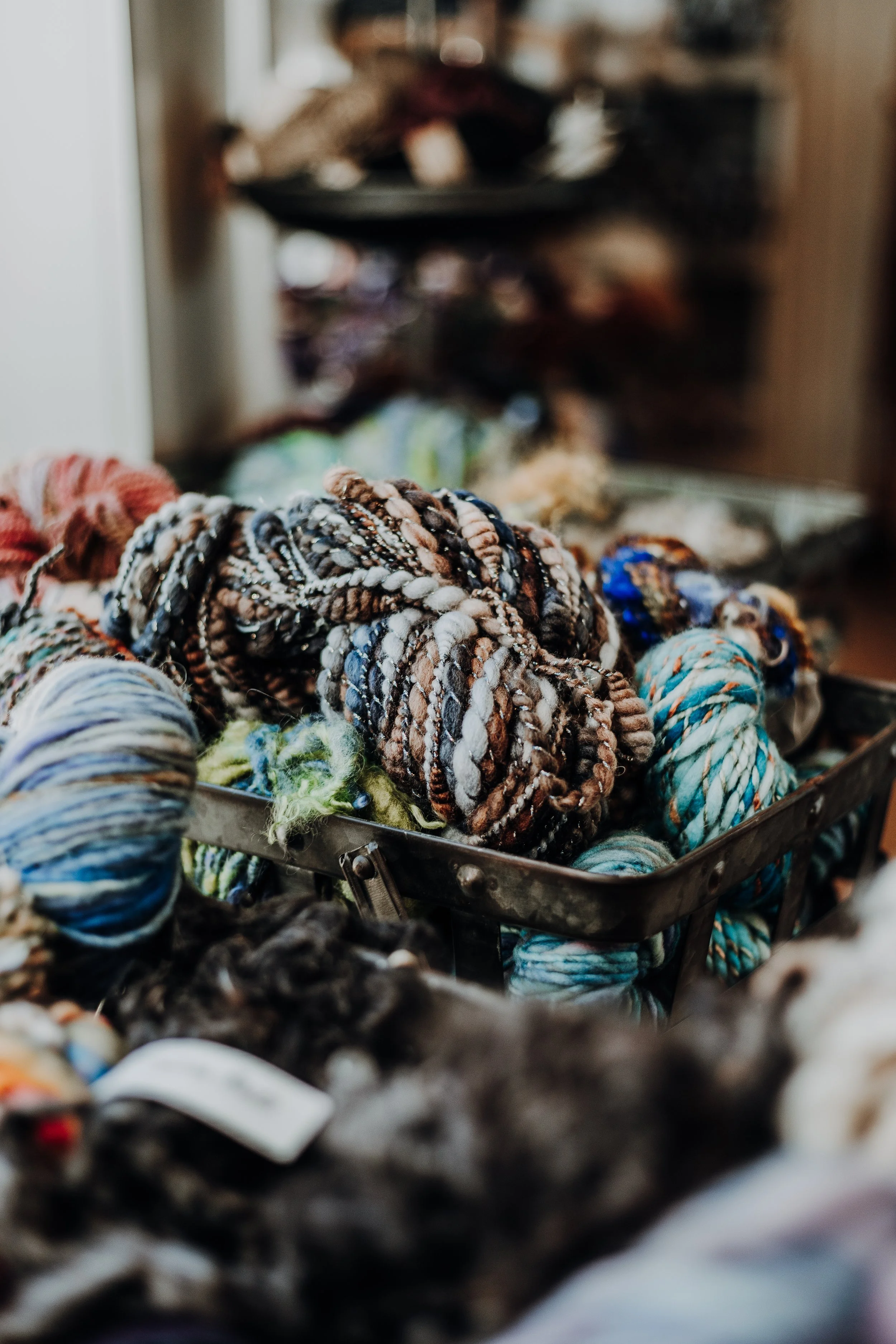 A basket of colorful, multicolored yarn in different shades including blues, browns, and whites.