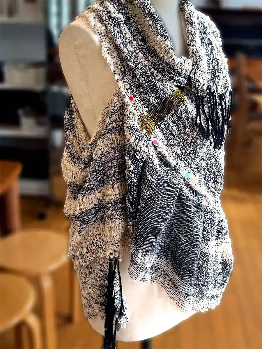 A black and white patterned scarf displaying on a beige mannequin bust in a cozy store setting.