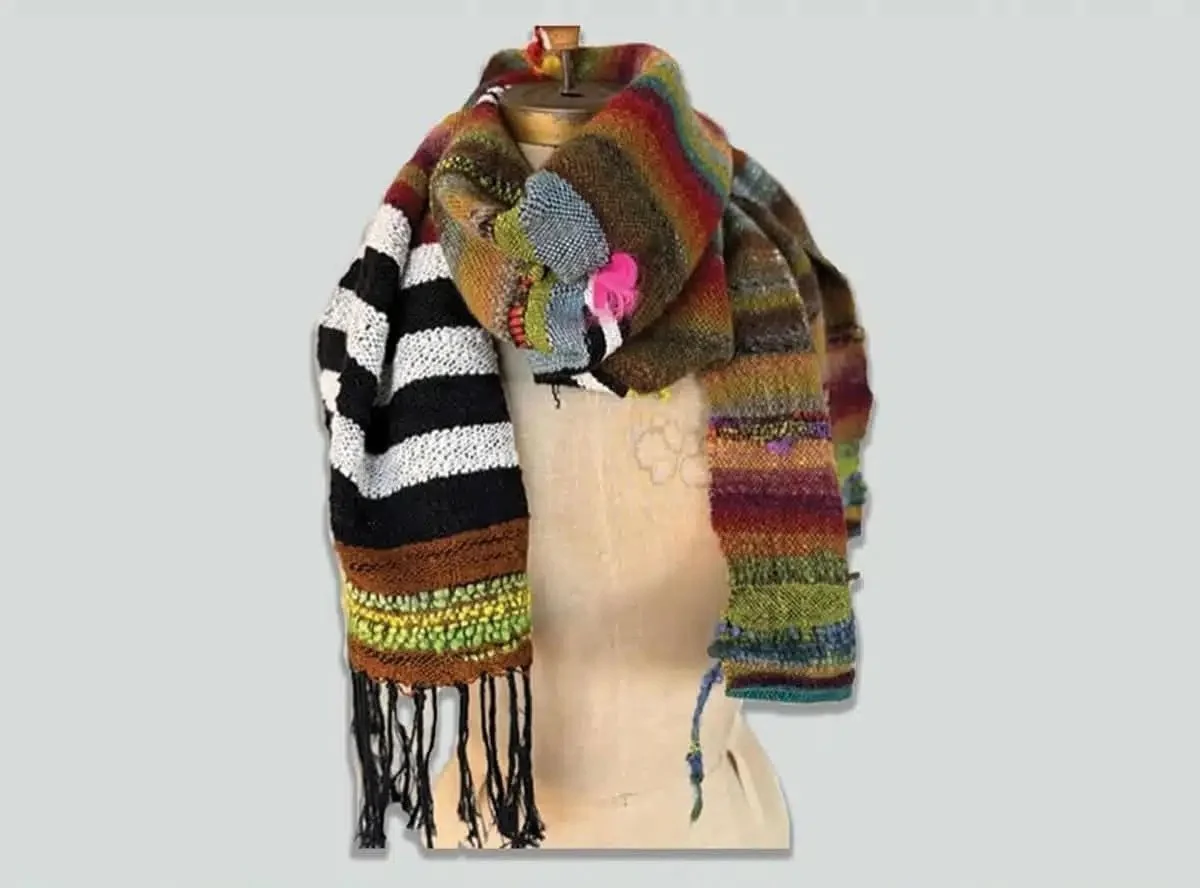 Colorful knitted scarf with various patterns and fringes displayed on a mannequin.
