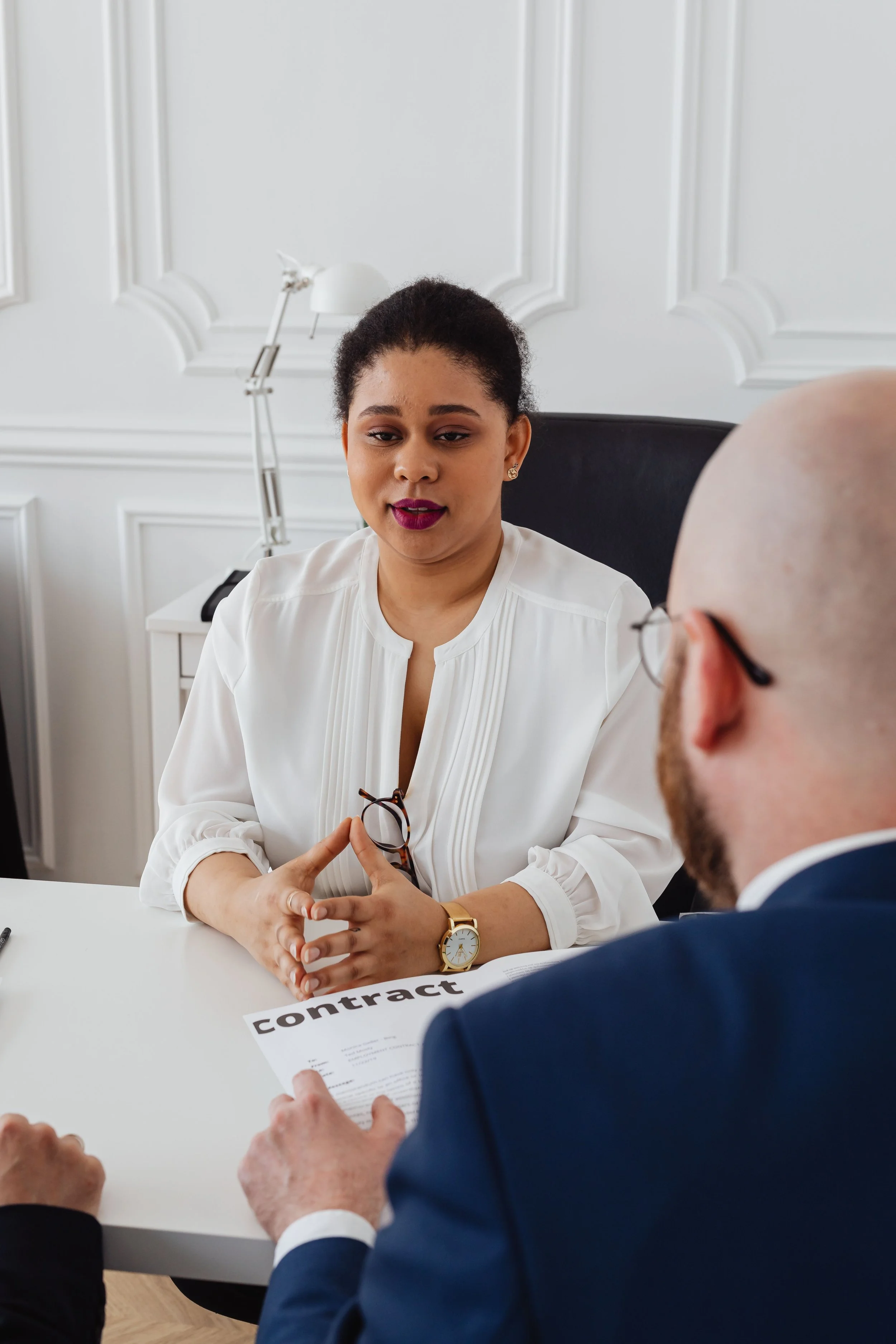 Businesswoman and man in formal attire discussing a contract during a meeting in a bright office.