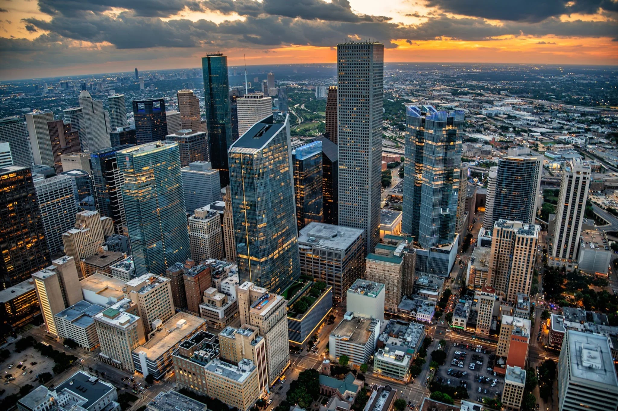 Aerial view of downtown skyscrapers at sunset with clouds overhead.