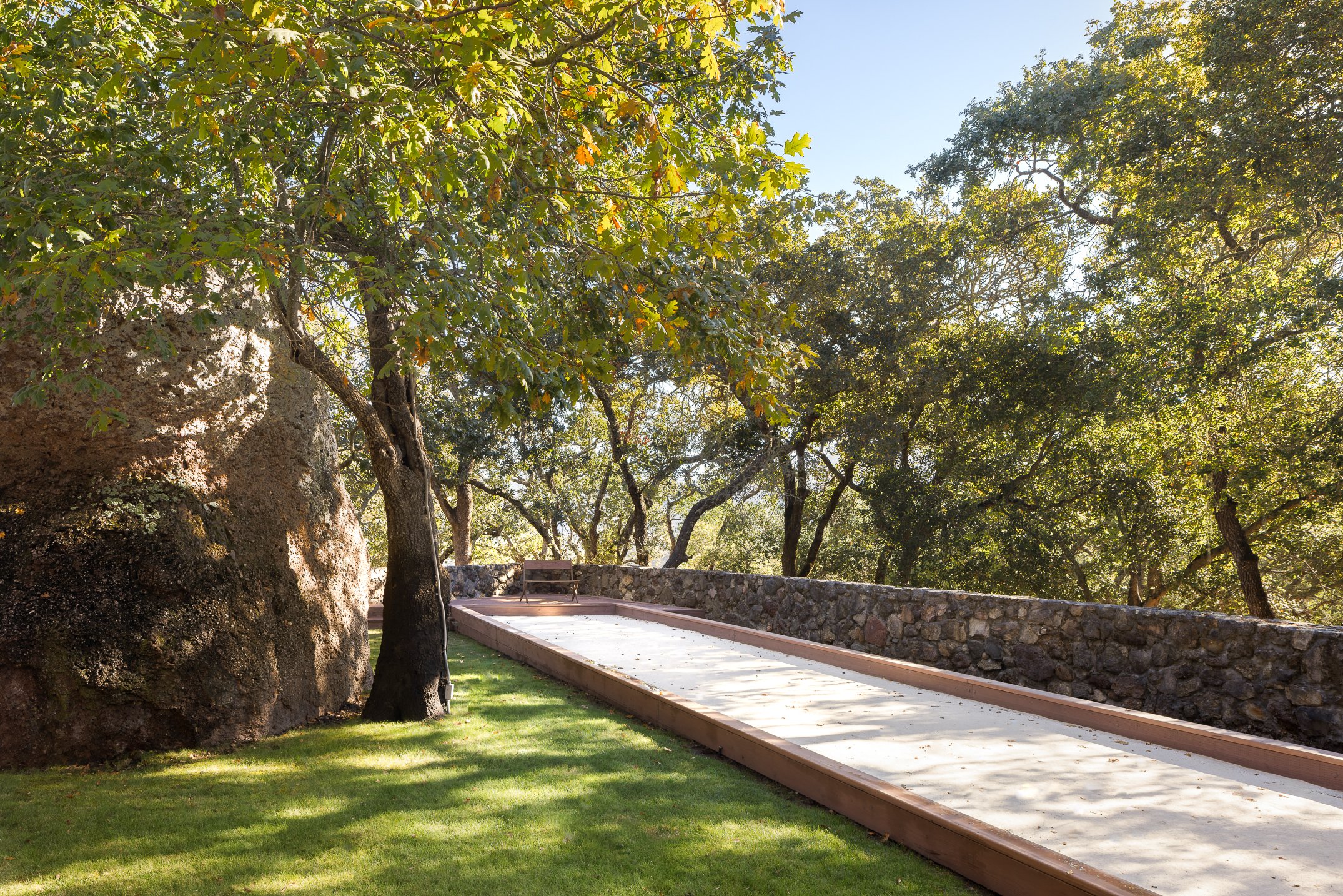 The Grove with a full-size boccee ball court, volcanic rock, and mature oak trees. 