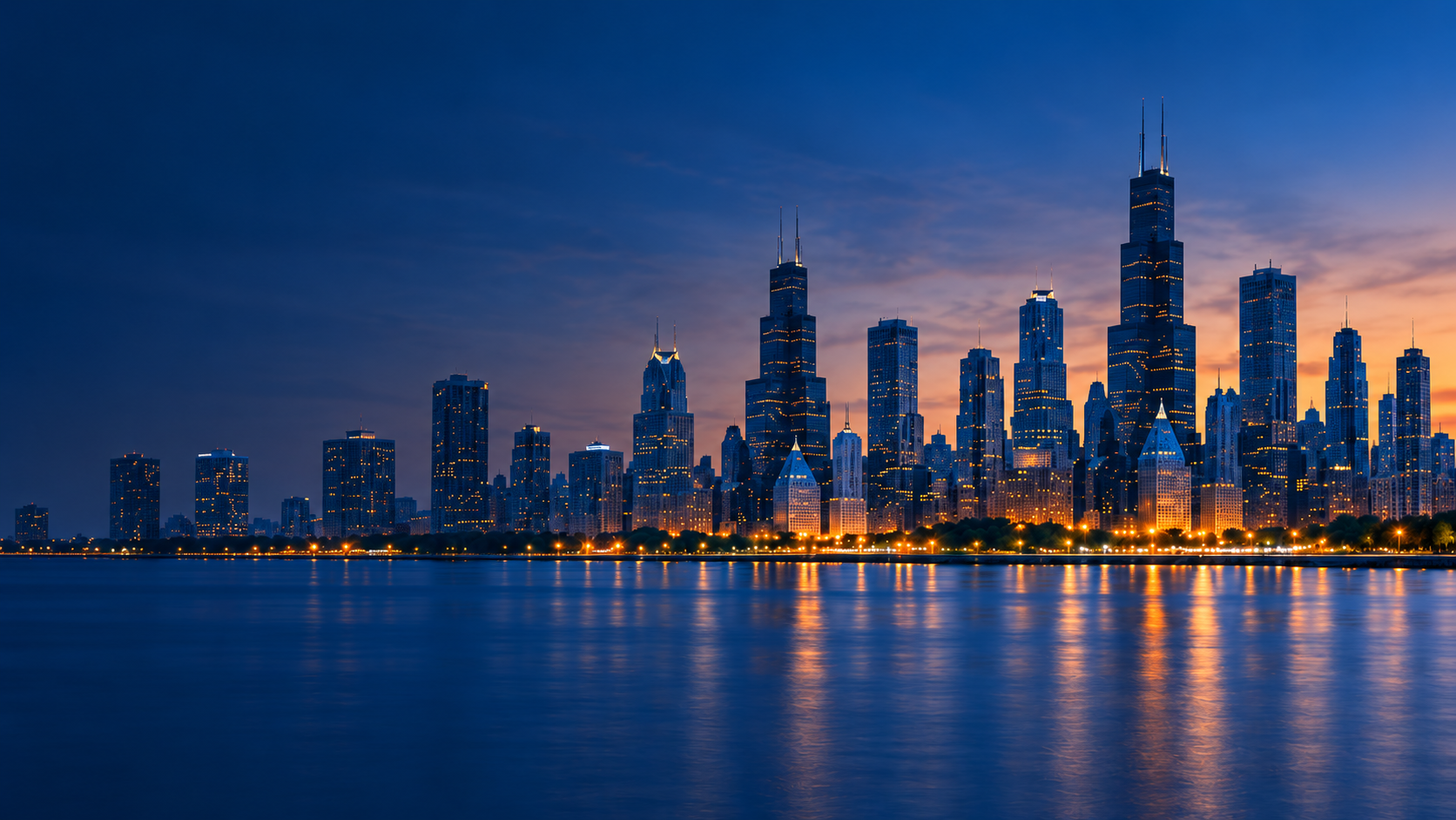 Chicago skyline at dusk with lit skyscrapers reflected on the water.
