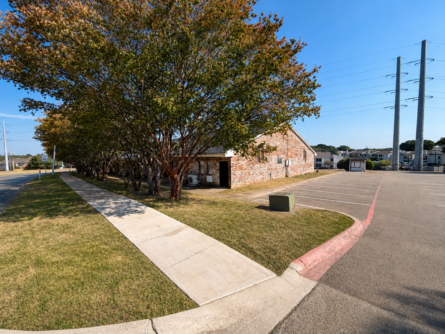 Beautiful tree-lined property exterior featuring spacious parking, sidewalk access, and a peaceful residential setting.