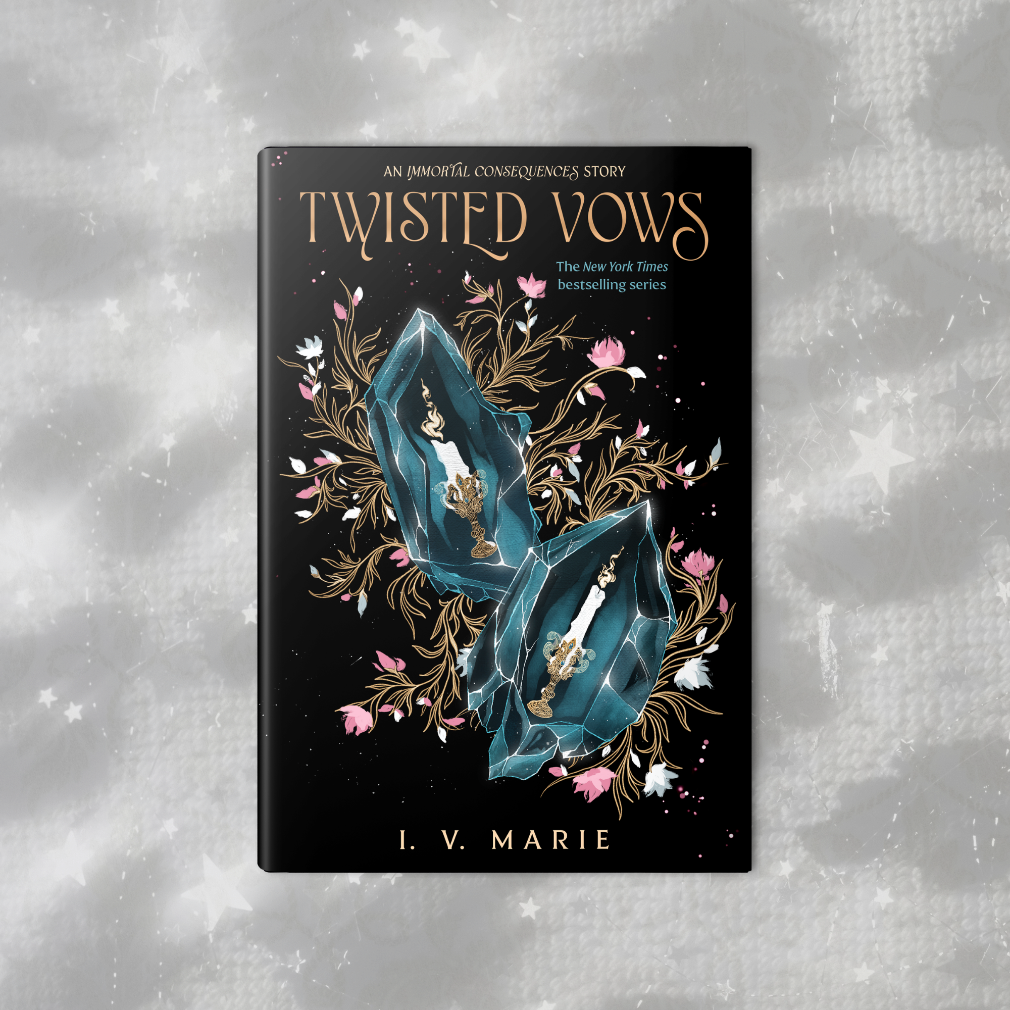 Close-up of a black book titled "Twisted Vows" by I. V. Marie, with an illustration of a blue crystal with golden details surrounded by pink and white flowers, on a starry, glittery, silver background.