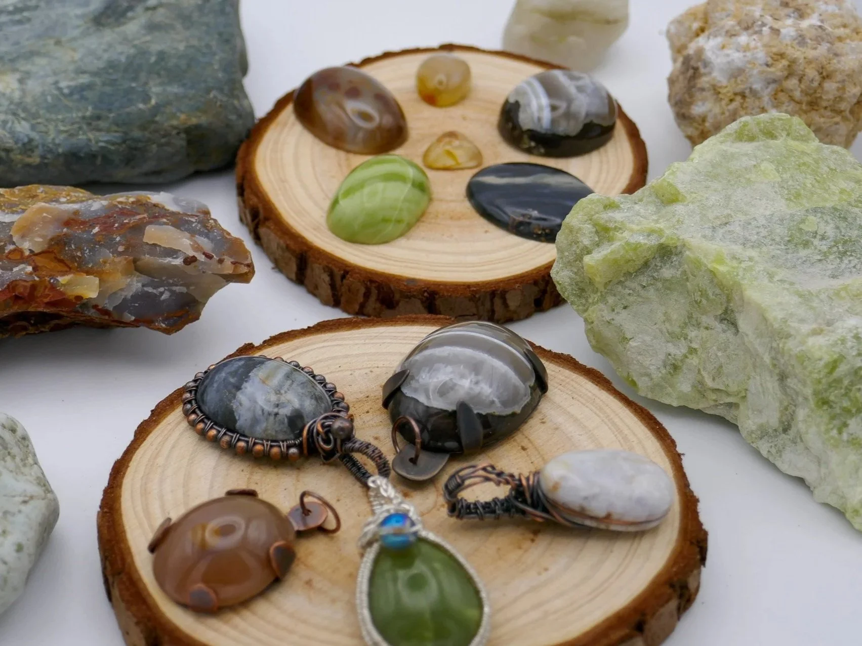 Various polished stones and crystals on wooden slices and a white surface.