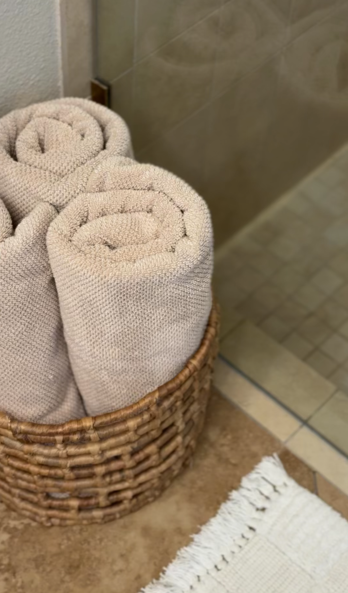 Three rolled beige towels in a woven basket in a bathroom in Palm Springs vacation rental
