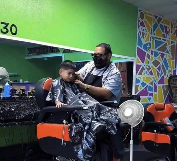 Juicy Cutz barber giving a child a haircut inside the Dickinson, Texas barber shop
