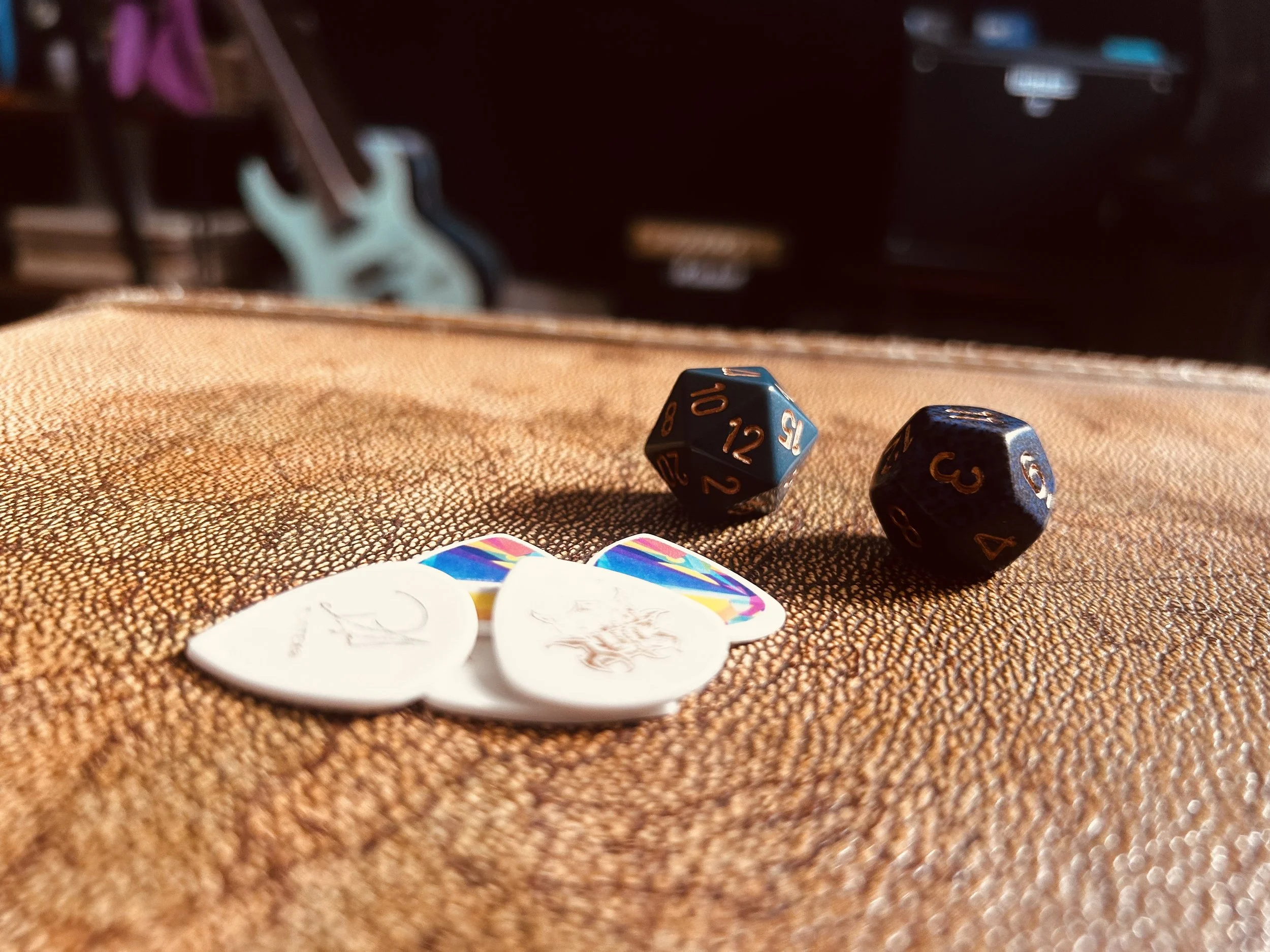 Close-up of two polyhedral gaming dice, one showing values 10, 12, 7, and the other showing values 7, 3, and 4, on a textured brown surface with a blurry background.