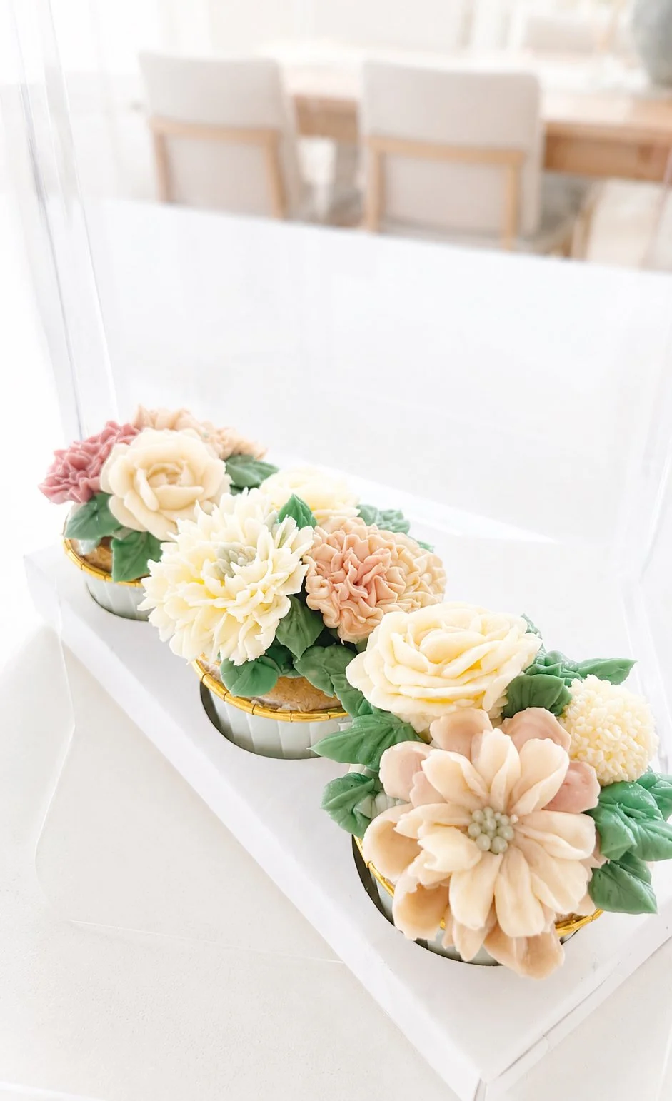 Decorative flower arrangement with luxury pastel-colored buttercream flowers and green leaves cupcakes.