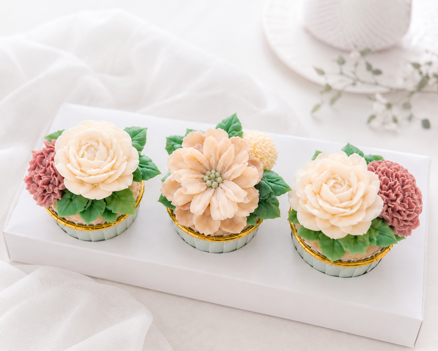 Elegant set of 3 buttercream floral cupcakes with hand-piped flowers in blush, ivory, and soft peach by J. Atelier Cake in Lehi, Utah.