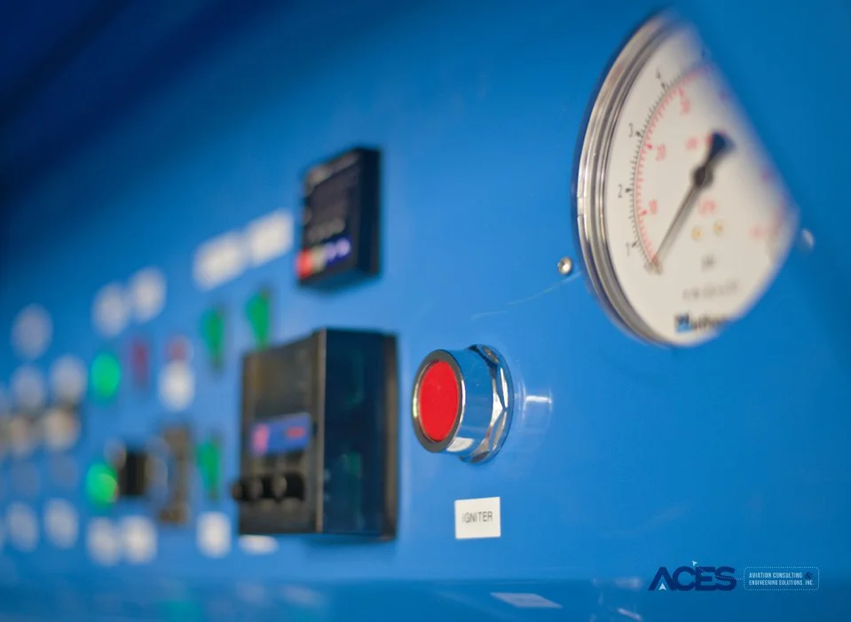 Angled view of an ACES Bunsen burner testing chamber control panel showing temperature displays, illuminated switches, timer, and pressure gauge.