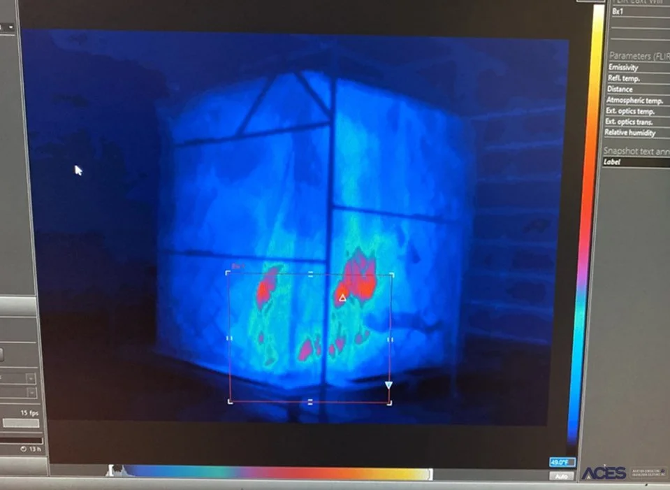 Thermal camera image of a fire containment test enclosure showing concentrated red and yellow hot spots against cooler blue surfaces.