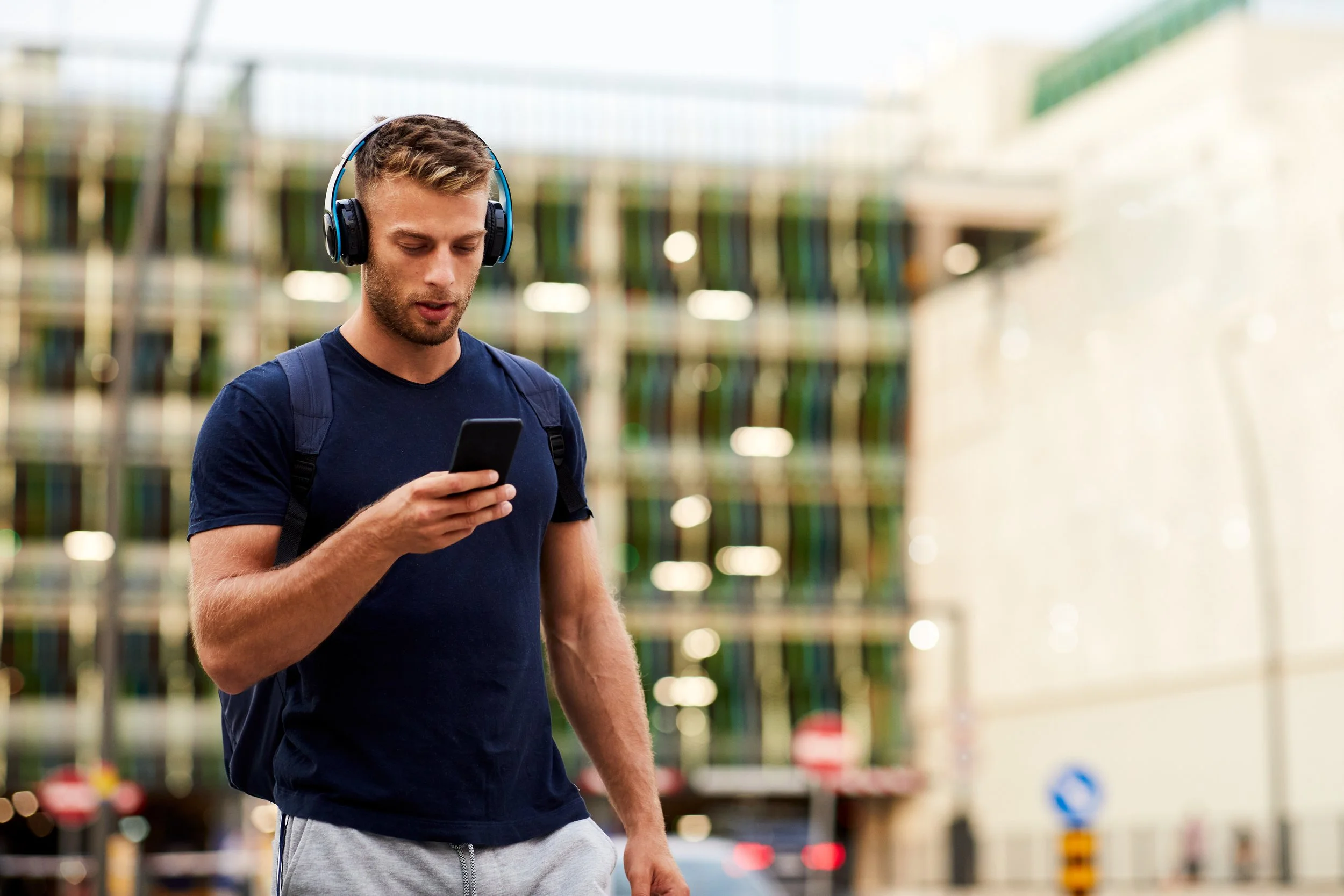 Young athlete watching an online class on his phone while walking out the training center.