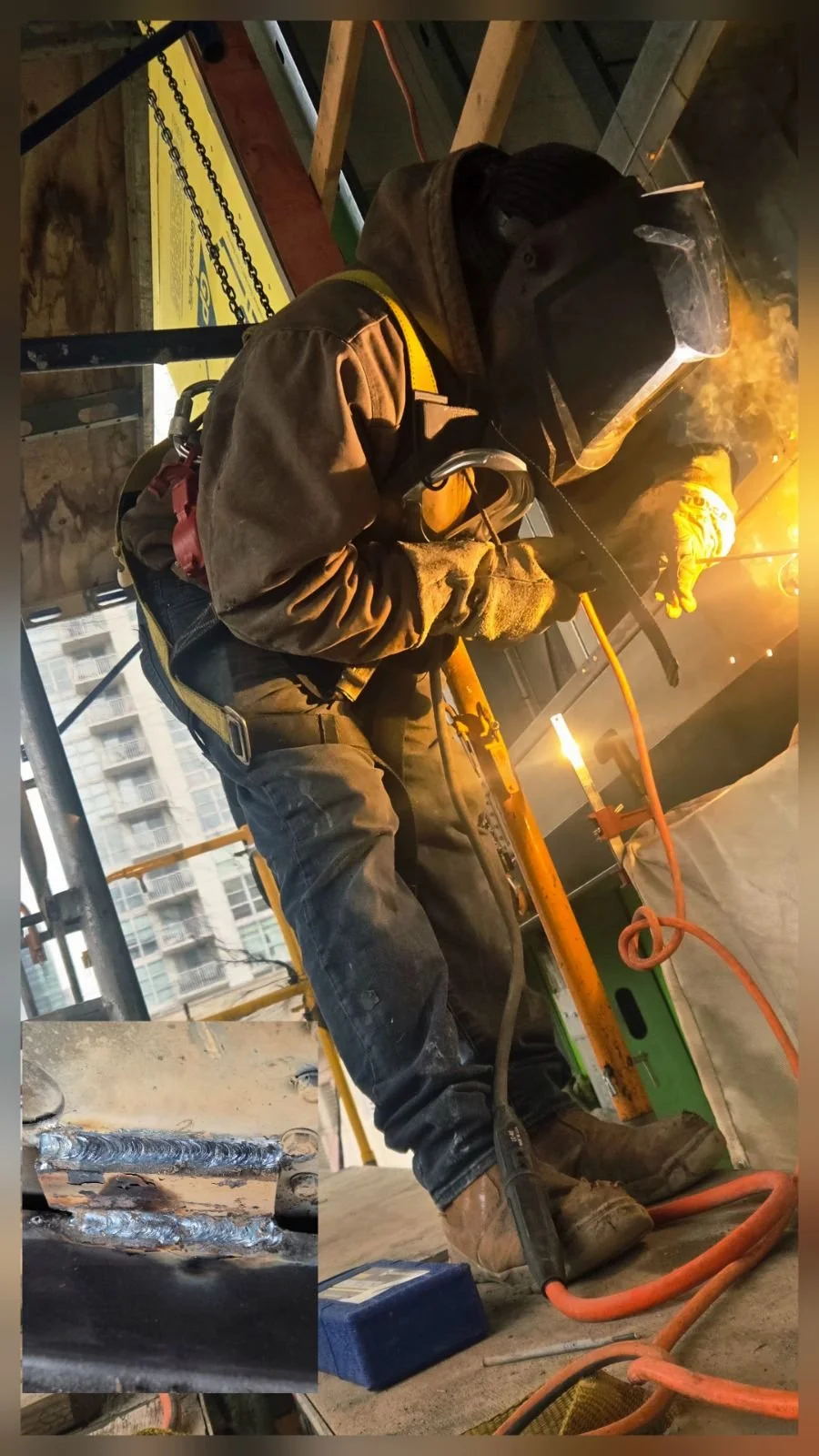 A construction worker welding metal on a construction site, wearing protective gear including a welding helmet, gloves, and work boots, with sparks flying from the welding process.