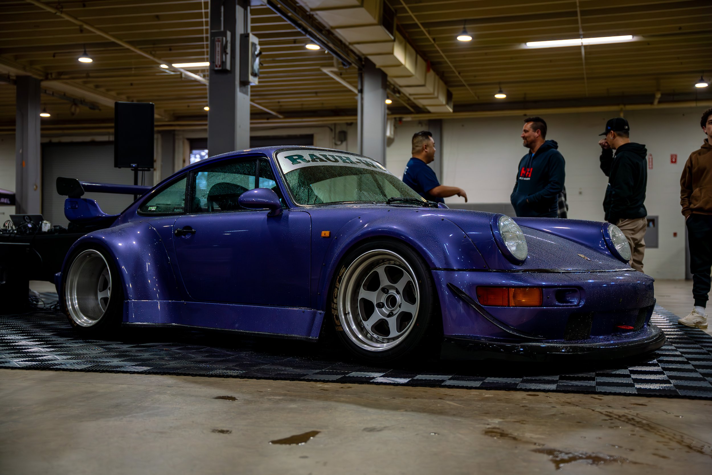 Blue Porsche photographed at an indoor automotive event.