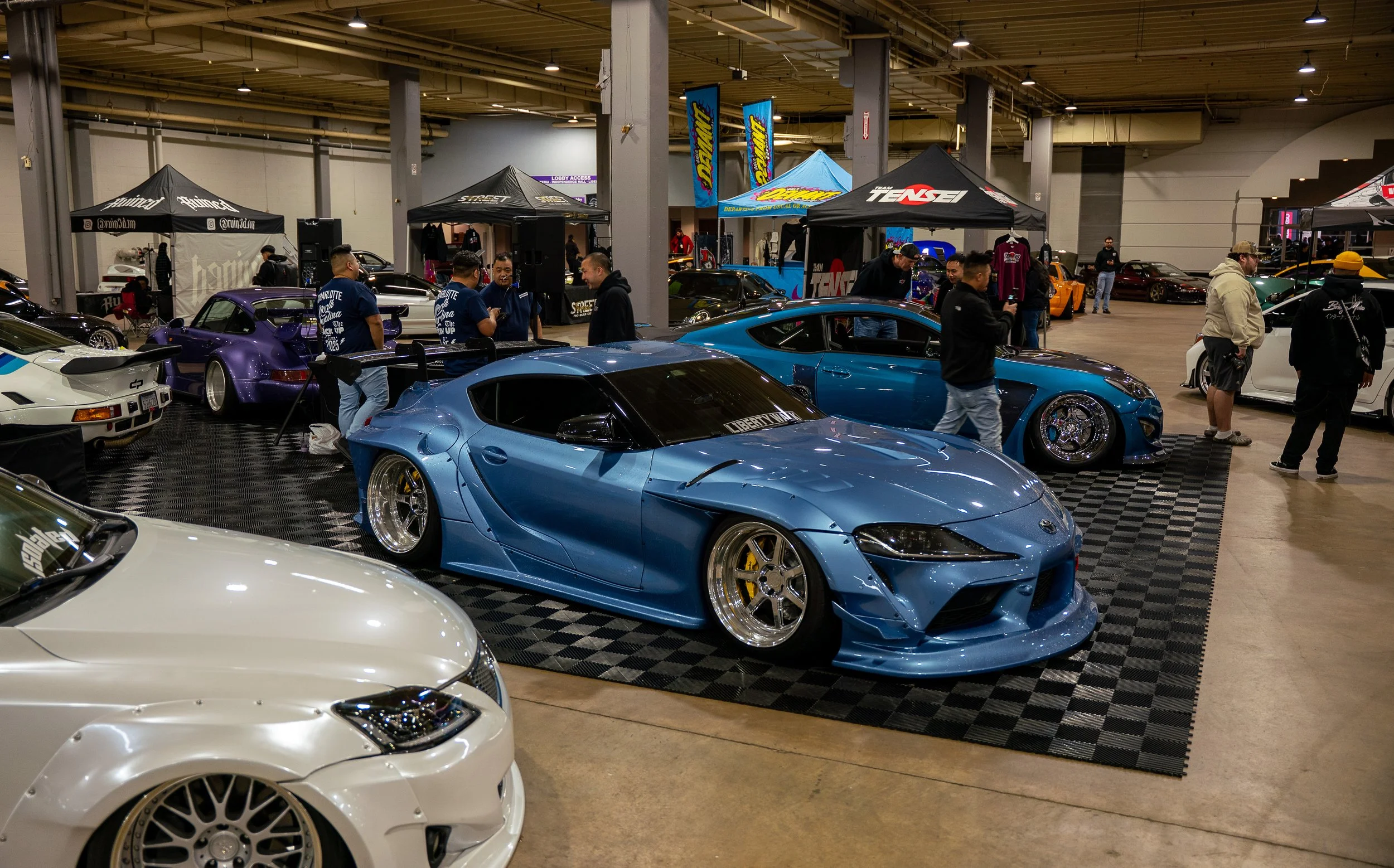 Indoor automotive event featuring custom sports cars and attendees, photographed by Hurley Media. 
