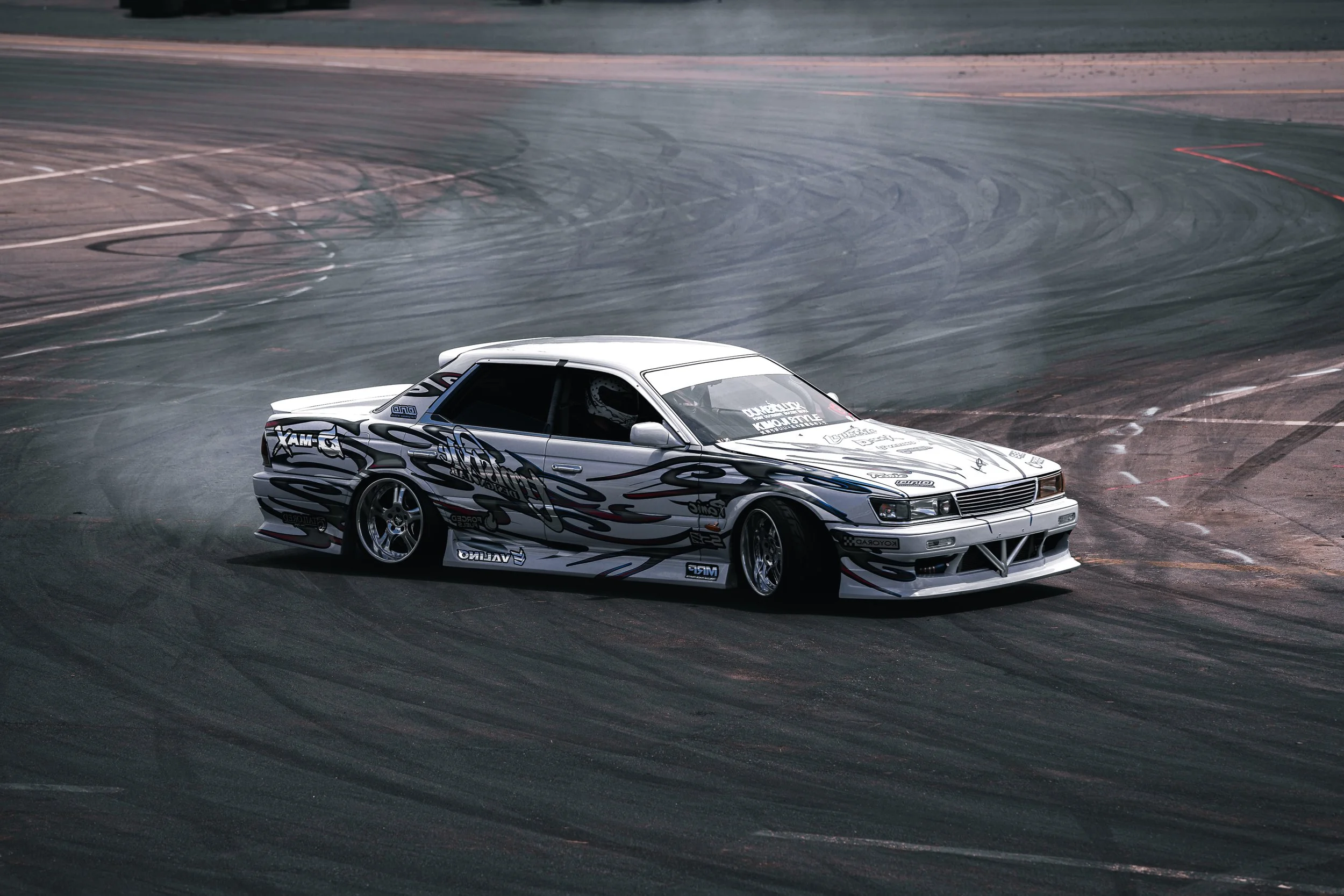 White drift car sliding through a corner at a motorsports event, captured by Hurley Media. 