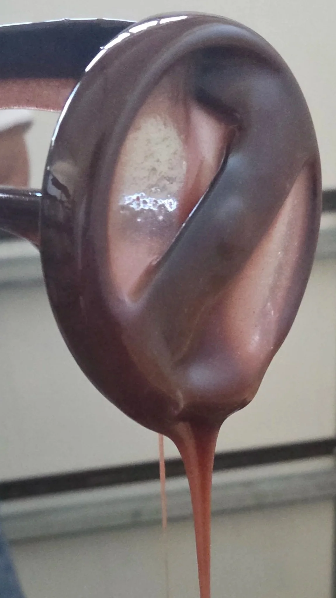 Close-up of melted chocolate dripping from a ladle.