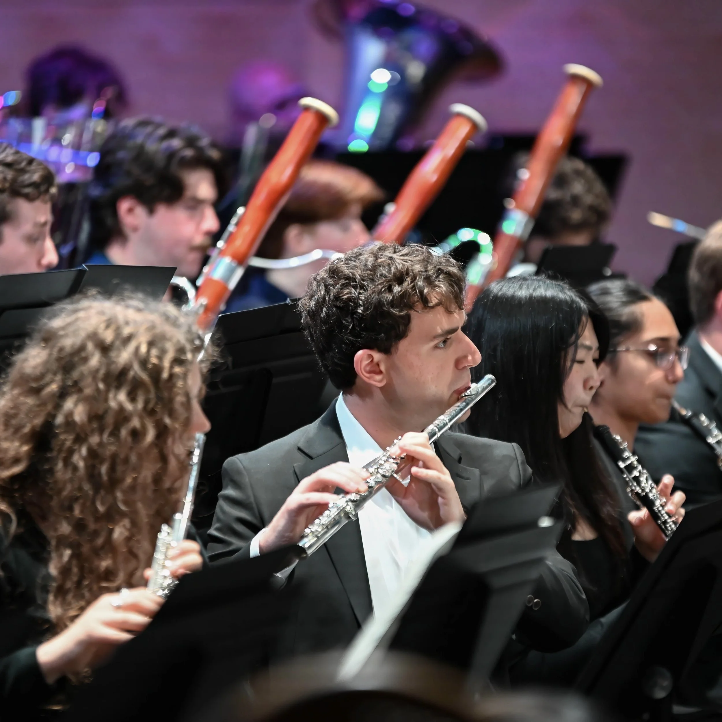 Symphony orchestra musicians playing flutes during a performance.