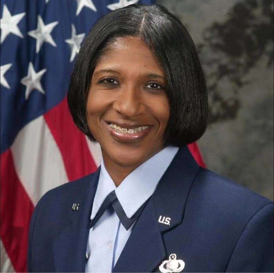 Dr. Amona Anderson, educator, veteran, and keynote speaker, at the beginning of her military career, in a U.S. Air Force uniform standing in front of an American flag.