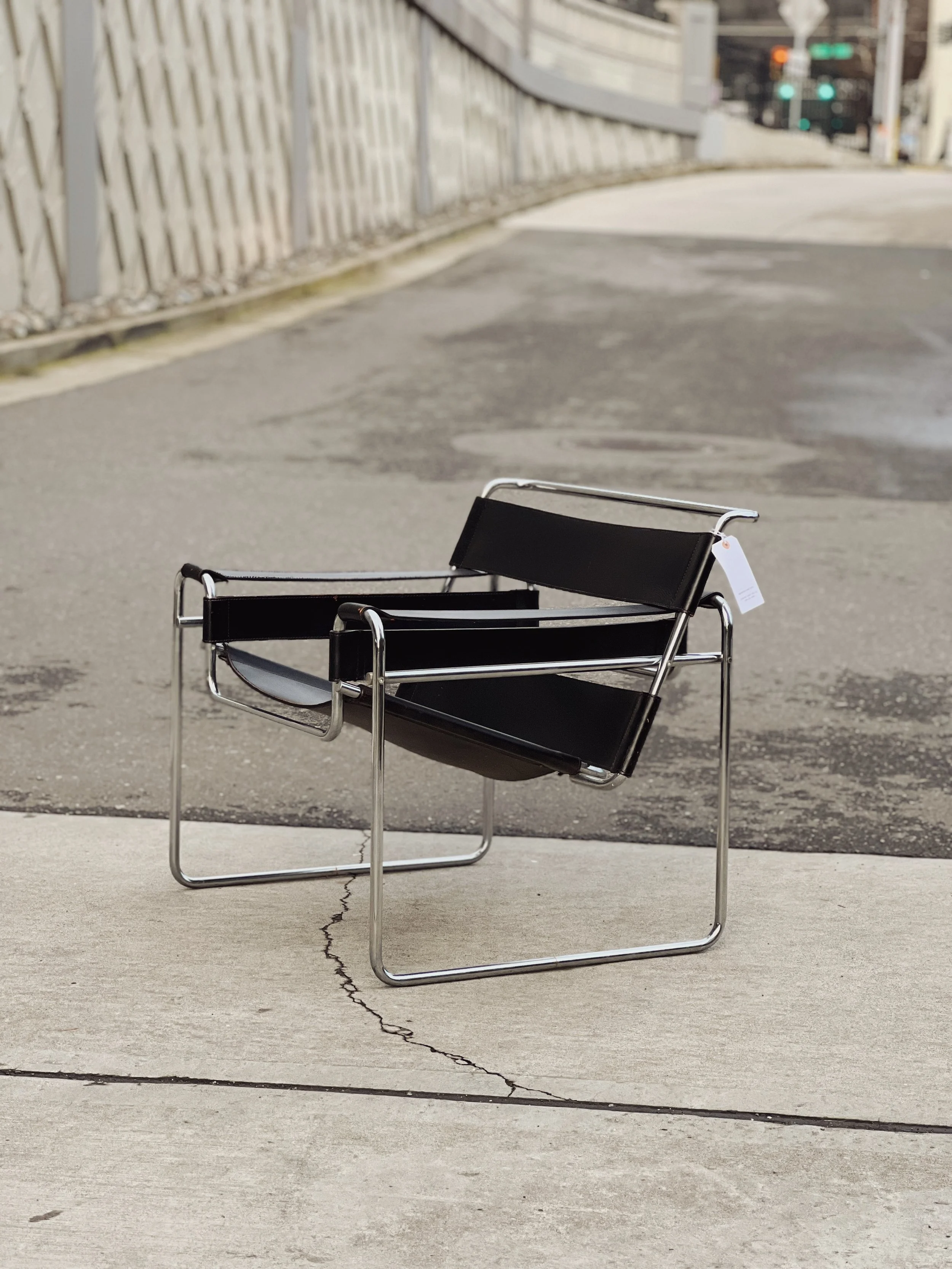 Two black and silver metal chairs with fabric seats and backrests placed outdoors on a concrete sidewalk.