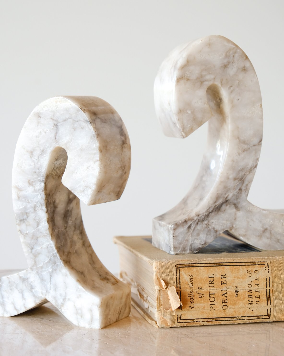 Marble sculptures of the numbers 2 and 9 placed on an old book with worn edges.