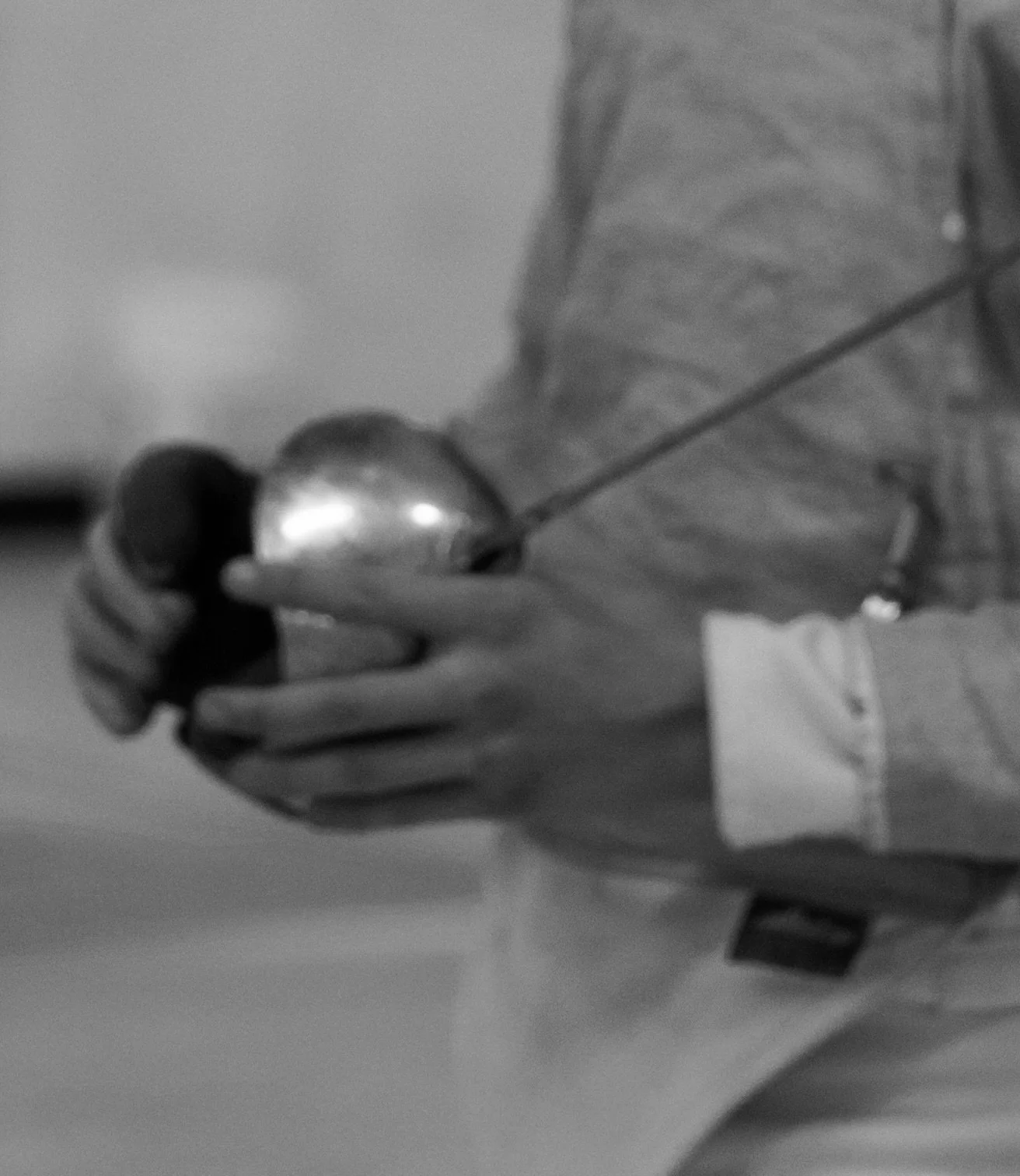 A person in a jacket holding a smartphone in one hand, with a closed umbrella in the other, standing indoors.