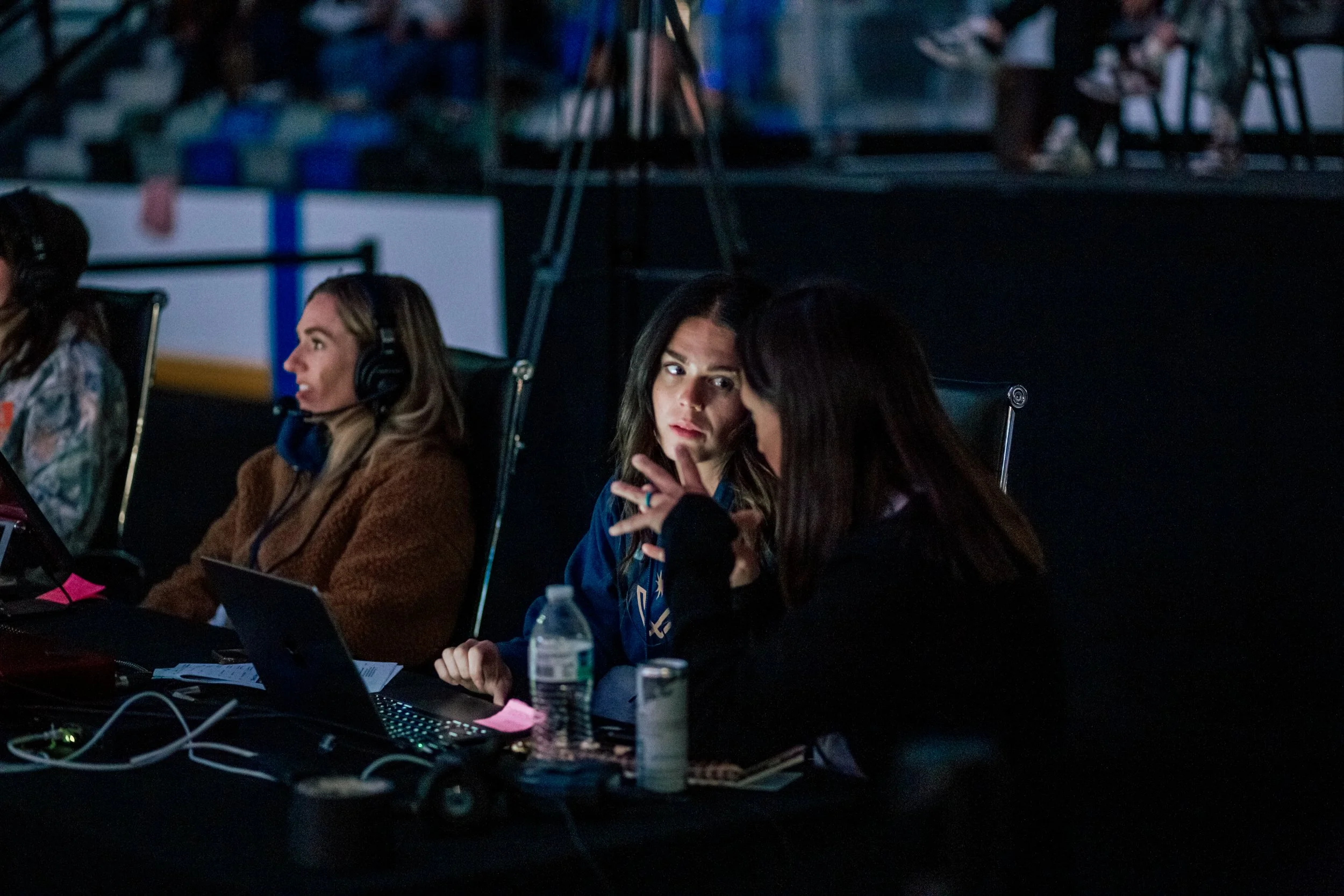 People sitting at a table during a meeting or conference, using notebooks and laptops, in a dimly lit room.Vetta Dance Project Expo