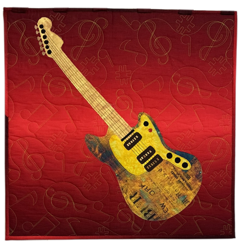 Decorative textile art featuring a stylized electric guitar with a yellow body, black pickguard, and a long neck, set against a red quilted background with musical note patterns.