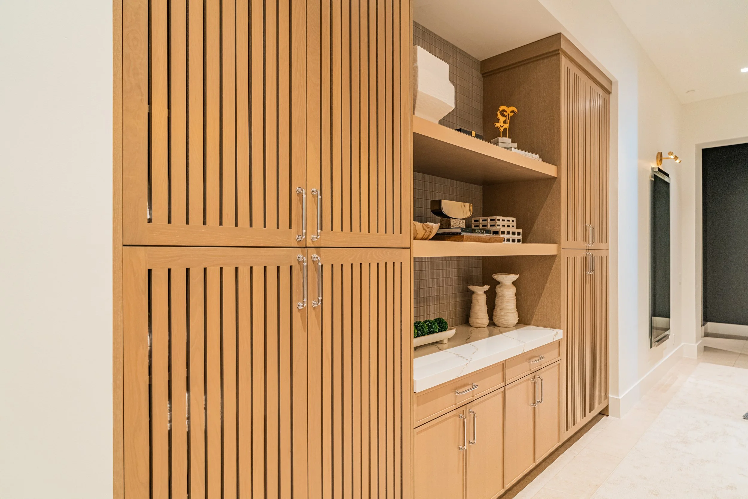 Wooden built-in shelves and cabinets with decorative objects such as bowls, sculptures, and plants, in a modern interior space.