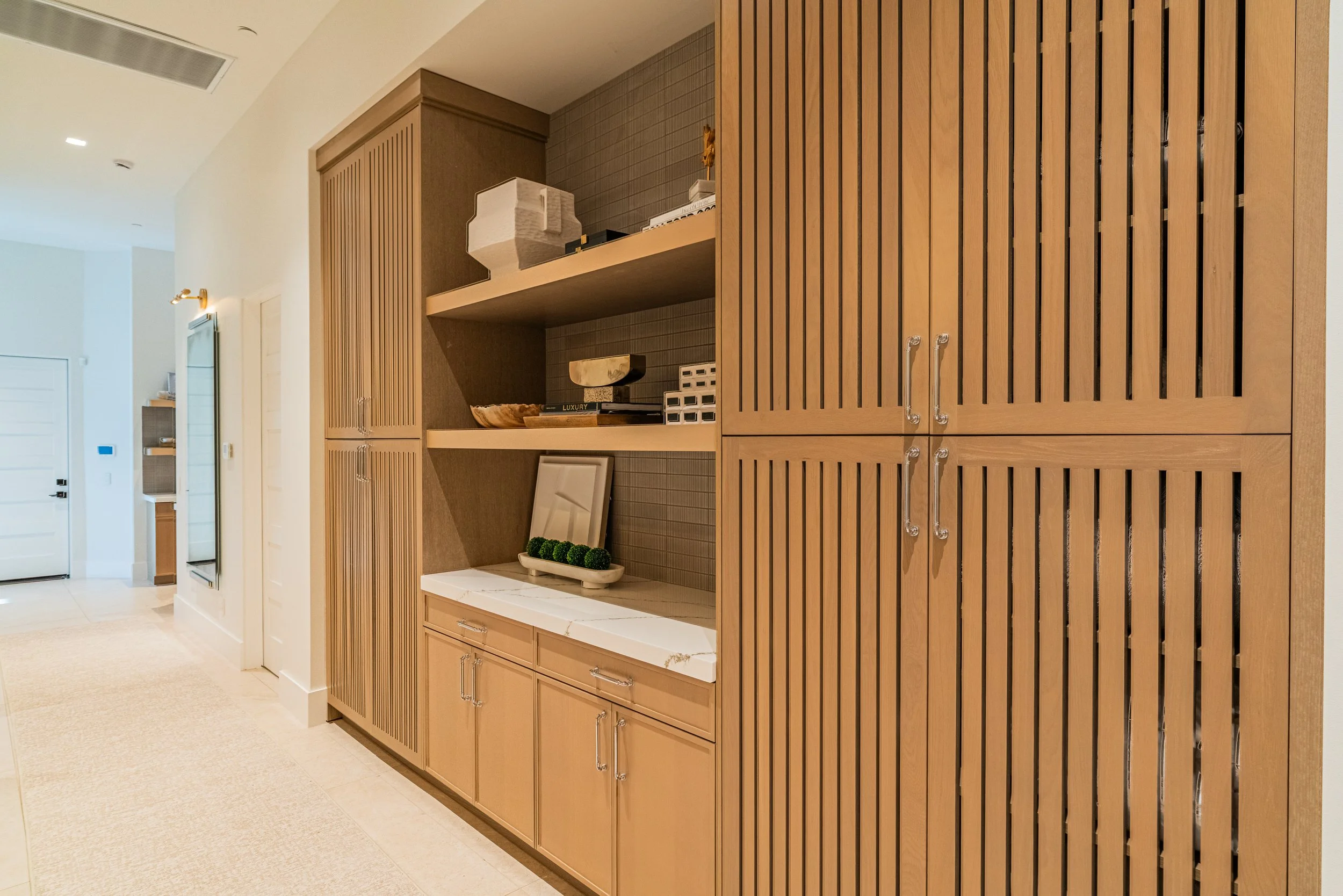 View of a built-in wooden cabinet and shelving unit in a modern home interior, with decorative items including a ceramic bowl, a small sculpture, and a book.