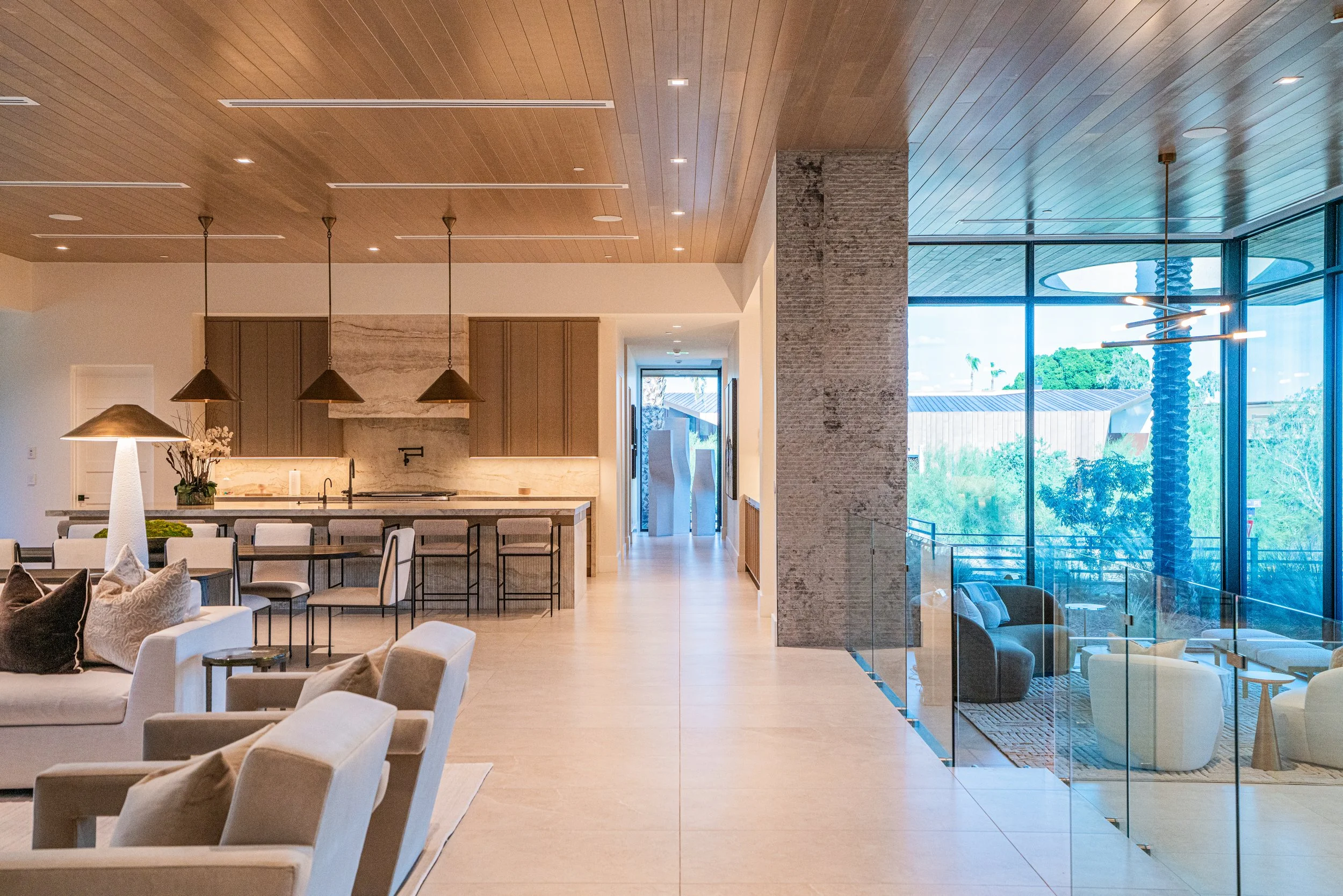 Interior of a modern living and dining area with wooden ceiling, large glass windows, and contemporary furniture.