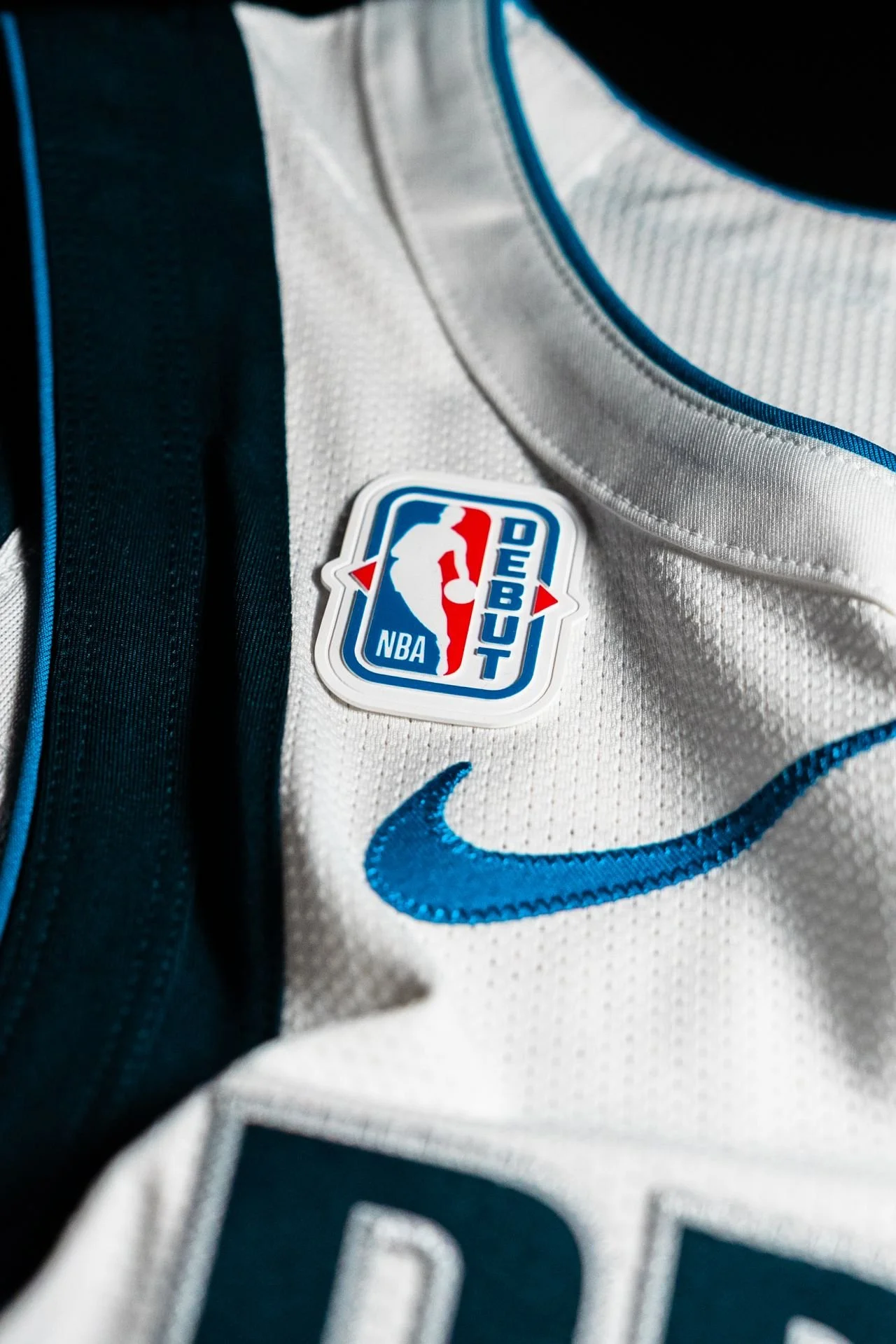 Close-up of the NBA Debut Patch on a white basketball jersey with blue and black accents, featuring the NBA and Nike logos.