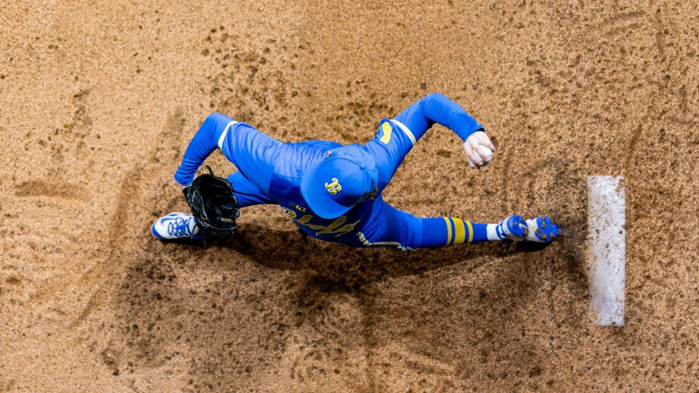 A baseball player in blue and yellow uniform sliding into home plate on a dirt field.